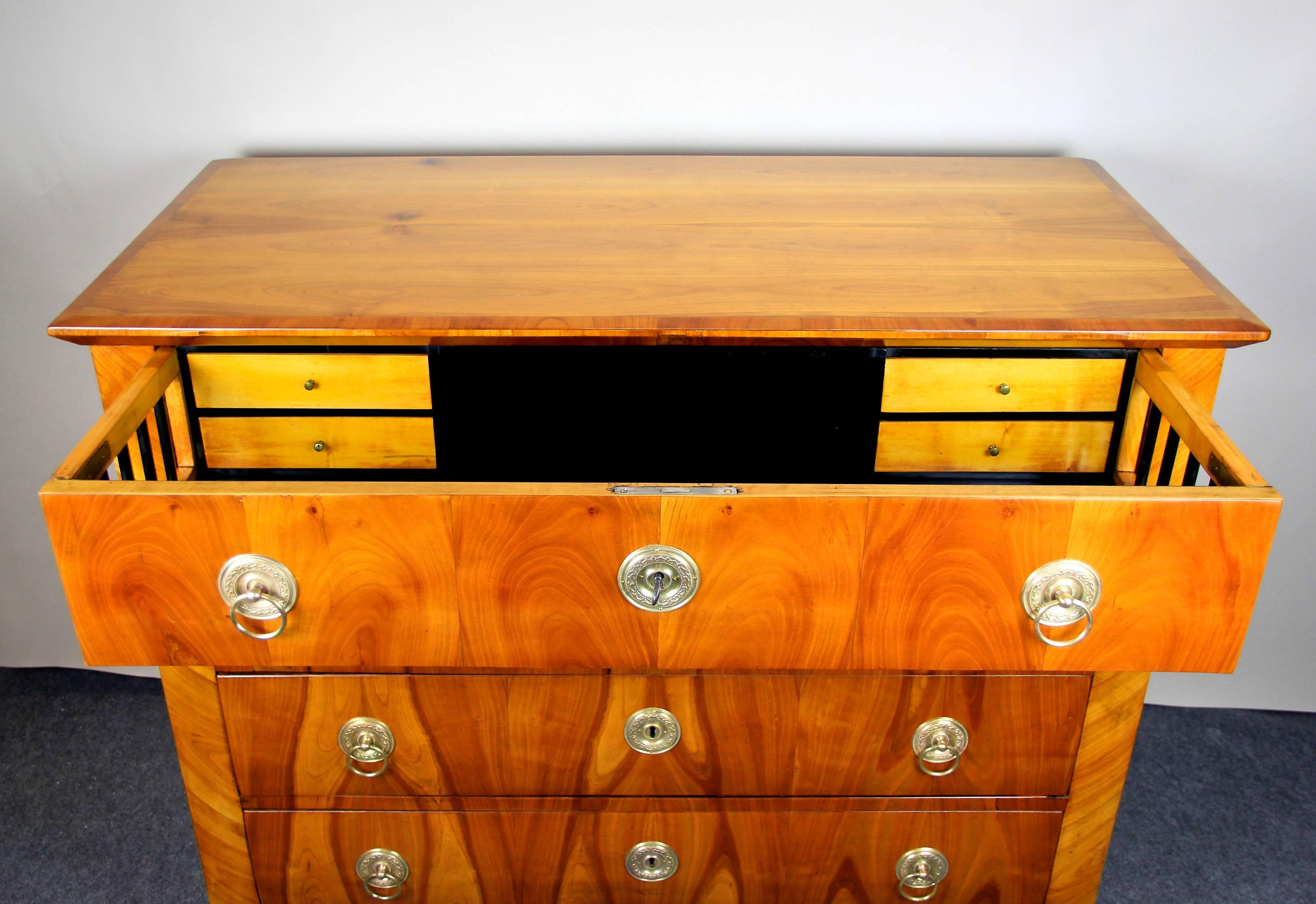 Fantastic cherrywood chest of drawers or writing commode from the Biedermeier period circa 1830 in Austria. Veneered in finest cherrywood by showing an outstanding grain, this perfect restored chest comes with four large drawers. The top drawer