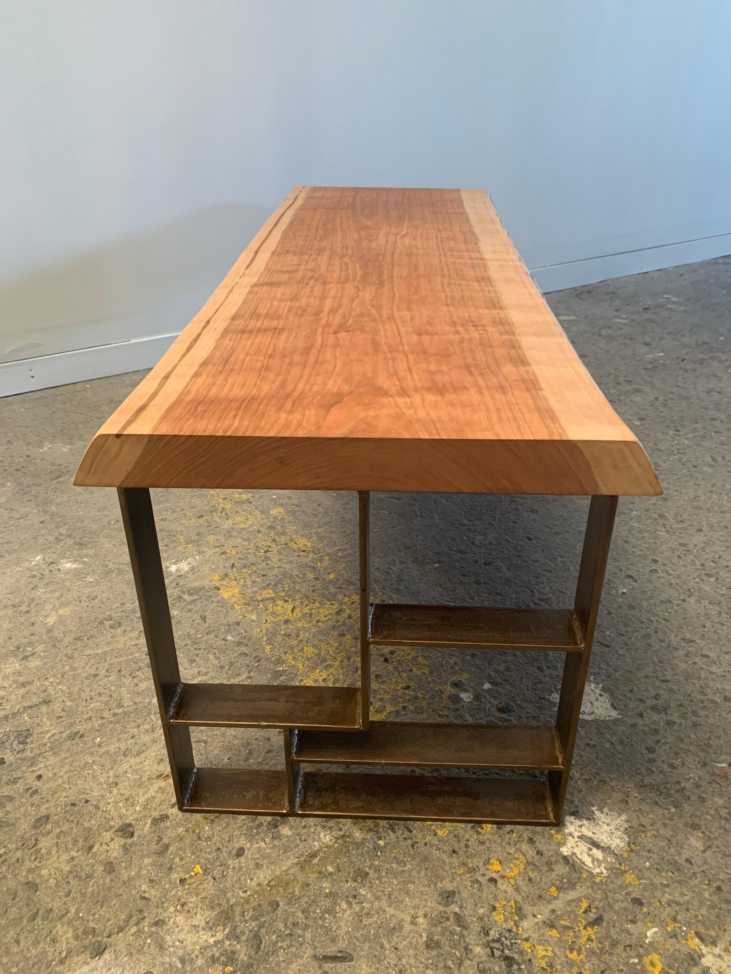 Handcrafted, natural cherrywood coffee table. The slab surface rests upon the handcut and welded steel base. A versatile steel magazine rack is seamlessly tucked under the table top further fortifying this rugged yet refined piece.

This piece is