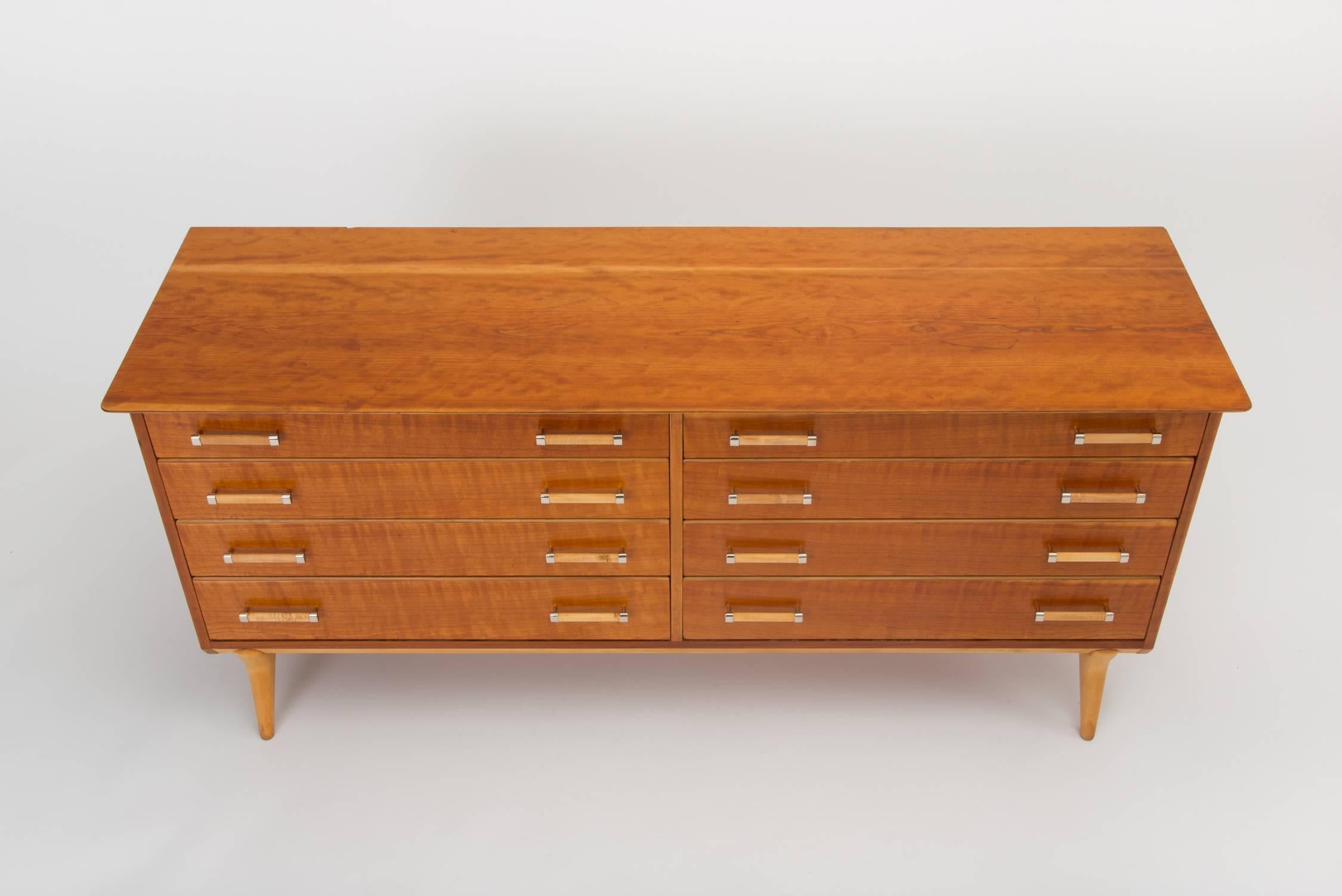 A stately modern dresser in subtly figured curly cheerywood with contrasting birch accents and brass fittings. Designed in the early 1950s for Johnson Furniture by longstanding creative director Renzo Rutile, and retailed by John Stuart in New York,