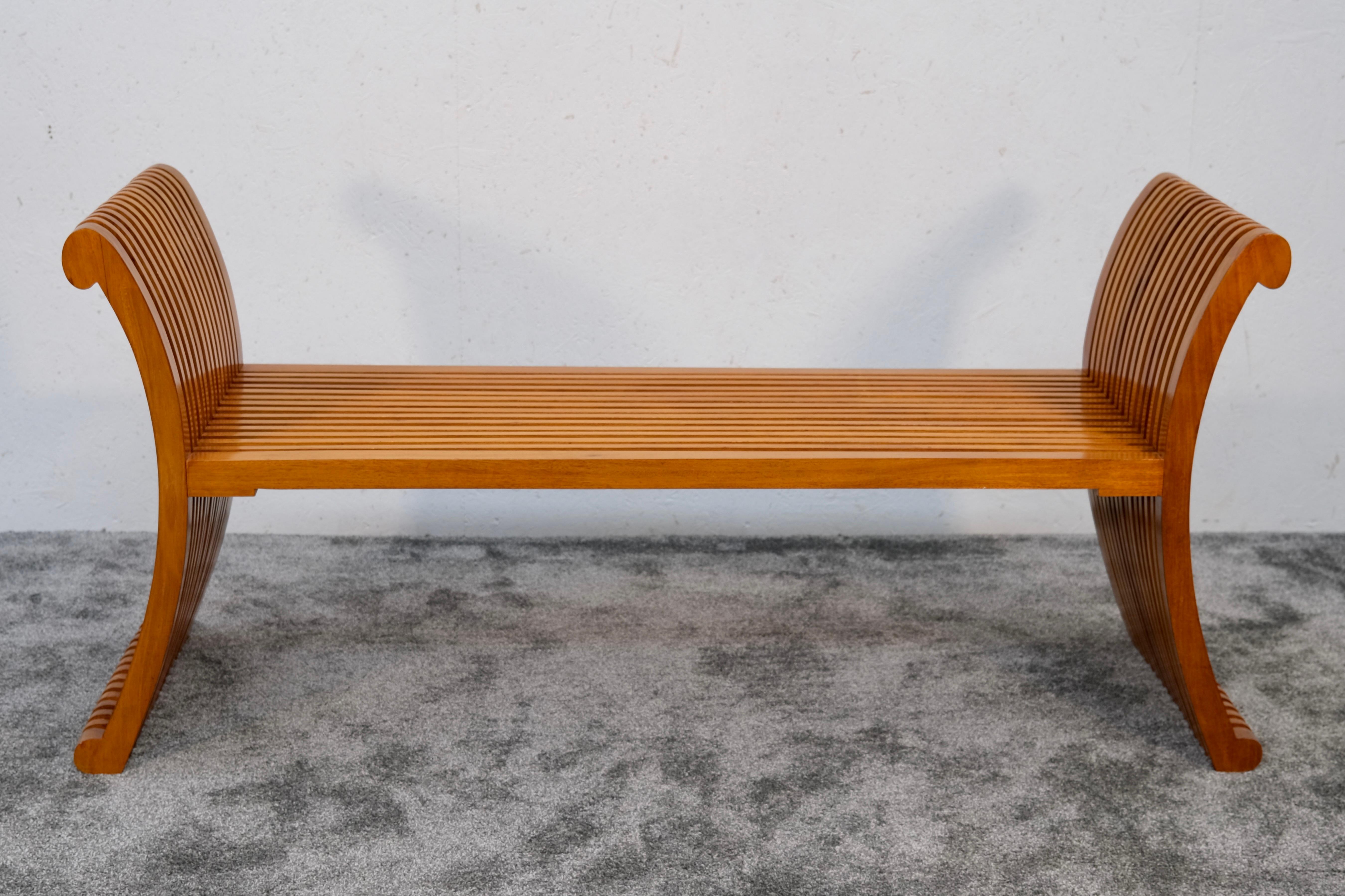 Ce banc sculptural des années 1990 impressionne par sa silhouette rythmée et fluide et sa structure magistrale - un équilibre raffiné entre fonctionnalité et art. Fabriquée en merisier massif, cette pièce présente des éléments latéraux gracieusement