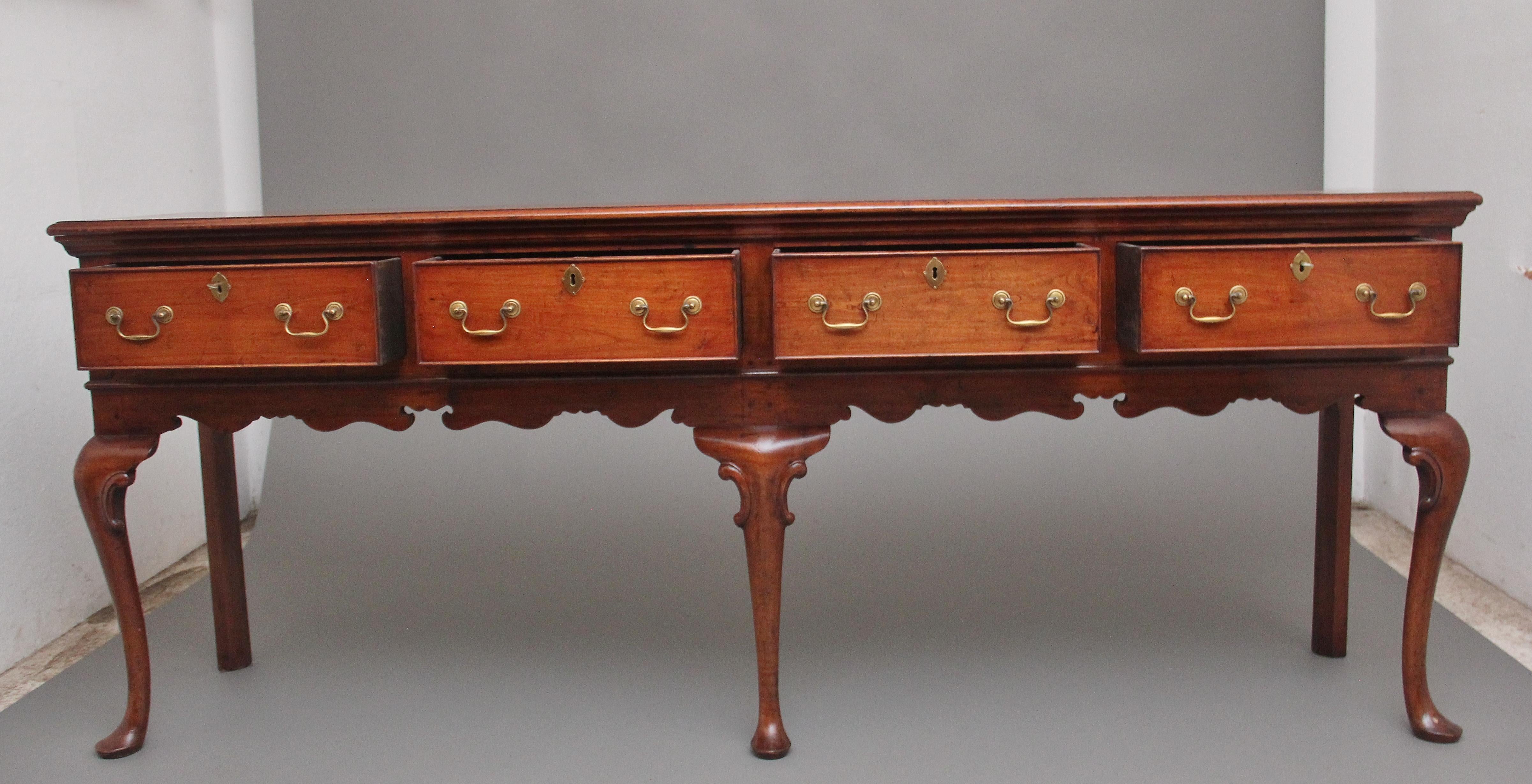 A superb quality Mid-20th century cherry dresser base in the Queen Anne style, having a nice figured and moulded top above four drawers with brass swan neck handles, oval escutcheons and workable locks, panelled ends, decorative shaped apron and