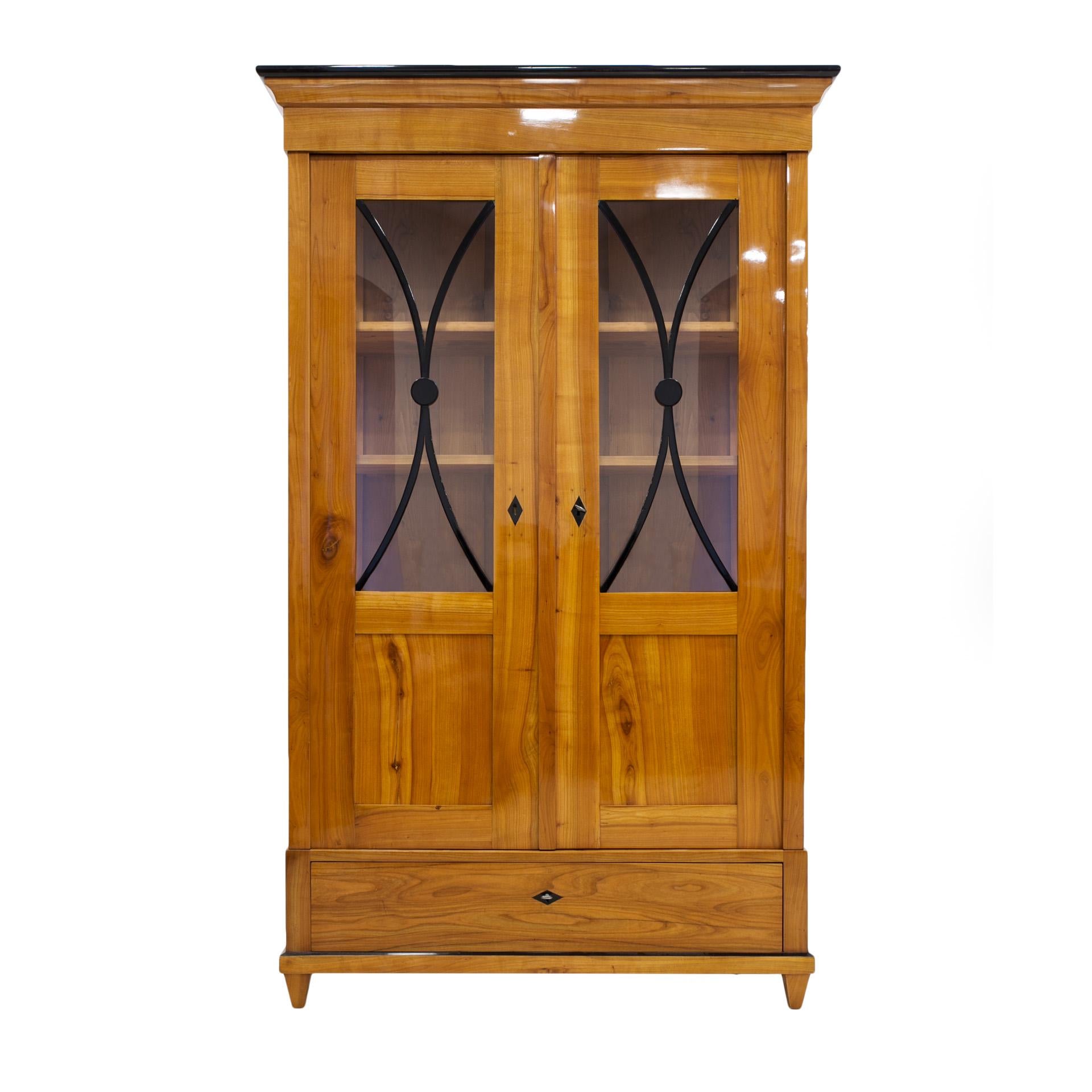 This beautiful cherrywood vitrine comes from Germany from 19th century (the Biedermeier period). The construction is made of solid cherrywood. The piece features practical shelves in the main sections and a spacious drawer at the bottom. It was