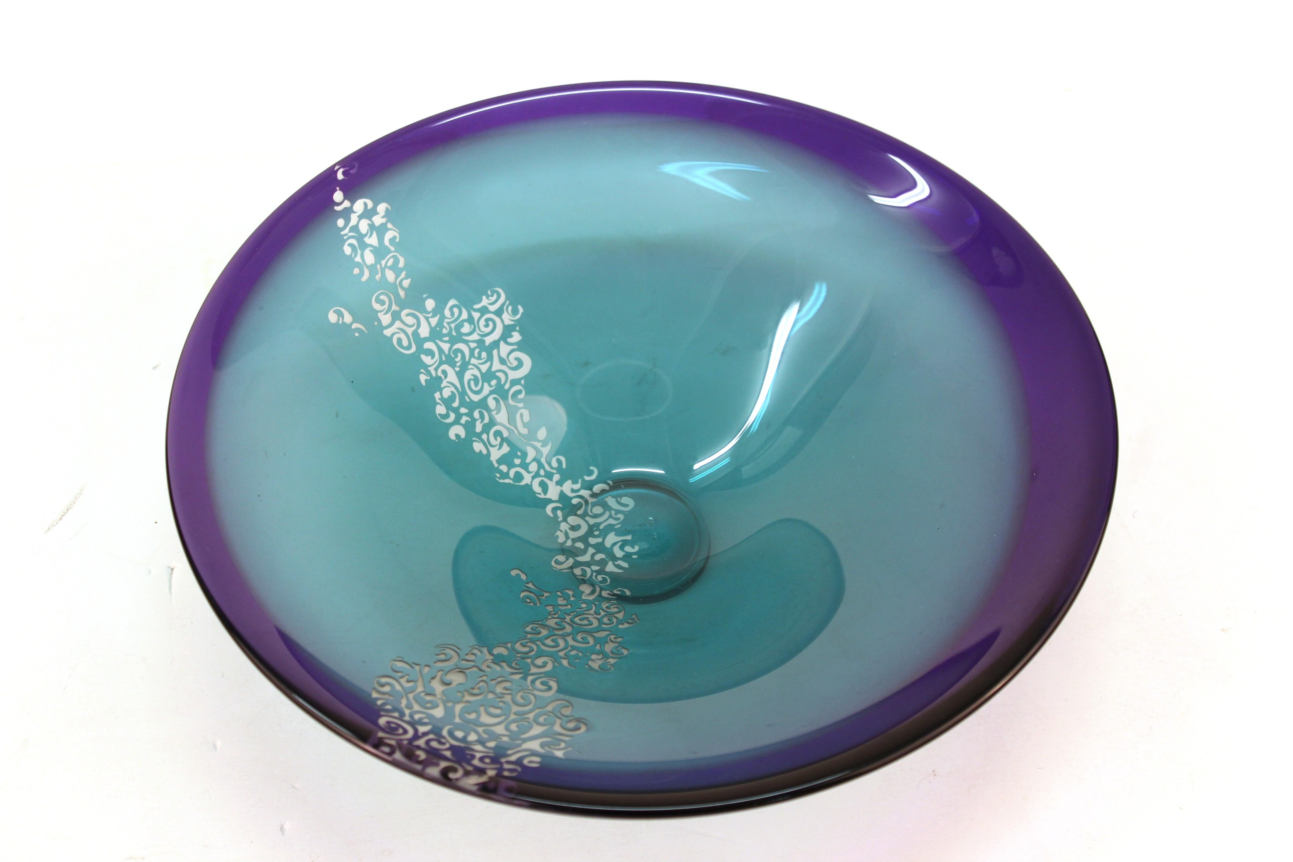 Canadian Modern studio art glass footed bowl in shades of turquoise to eggplant purple, sand blasted with a meandering band of swags, atop a glass foot. The piece was made by Canadian glass artist Cheryl Takacs and has the artists etched signature
