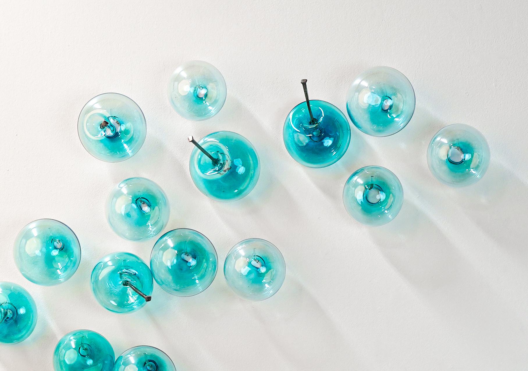 Esta escultura contemporánea de pared de cristal fue creada por Cheryl Wilson Smith. La artista es conocida por sus etéreas piezas de vidrio, a menudo inspiradas en la agreste belleza natural que rodea su hogar en el norte de Ontario. Esta serie