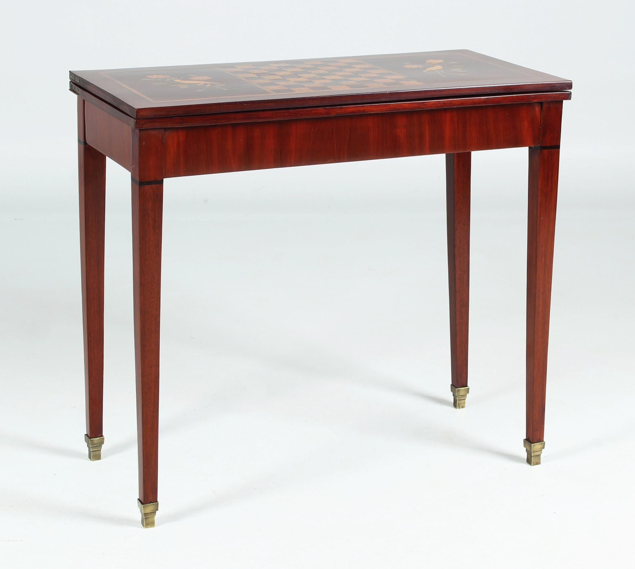 Antique chess and card table in Louis XVI style from the 19th century.

When closed, we see a console table standing on long pointed legs and in brass sabots.
The top is divided into three sections by thread inlays. On the left and right we see a