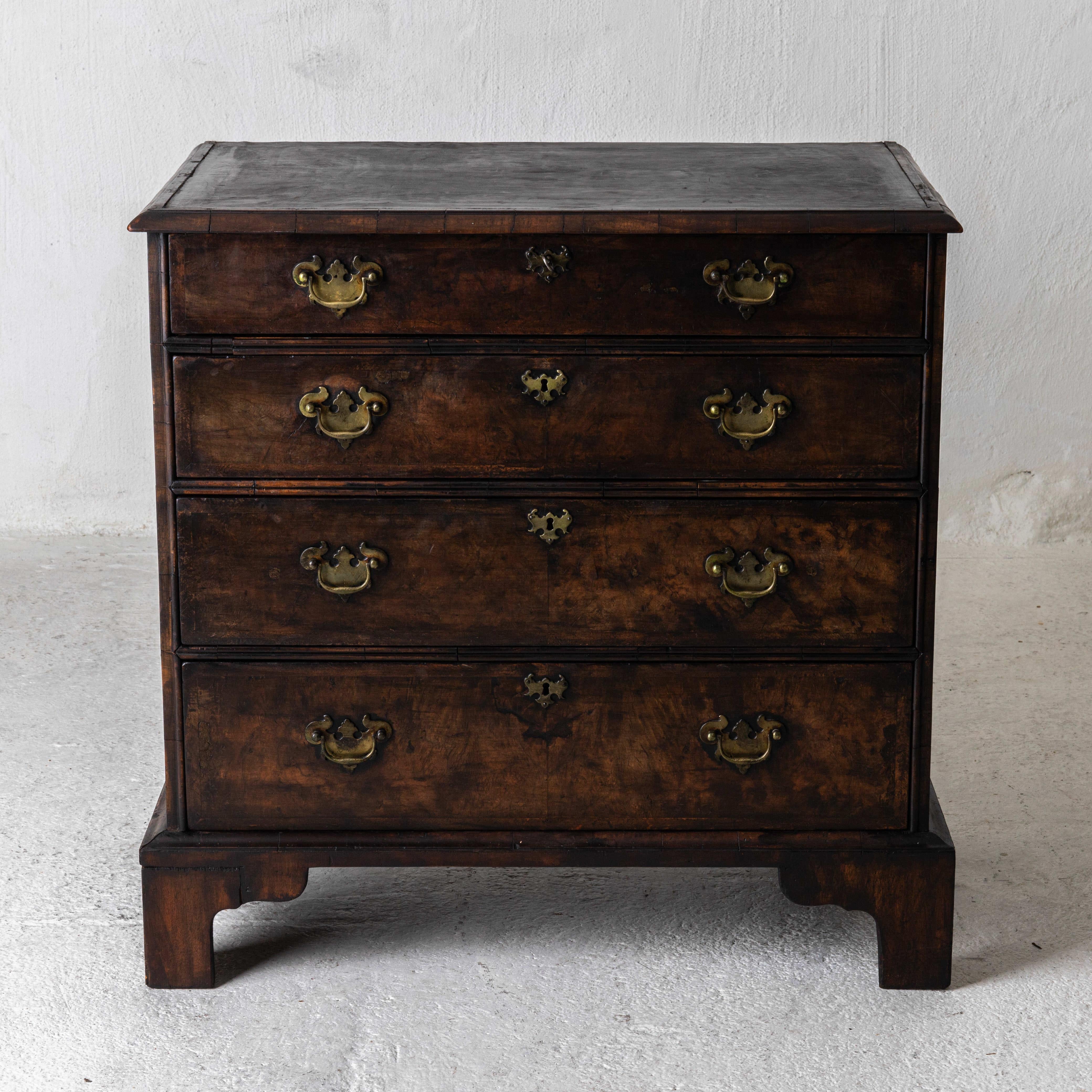 A chest of drawers made during the 19th century in England. Dark brown with brass hardware. A total of 4 drawers. Leather inlay on the top.
