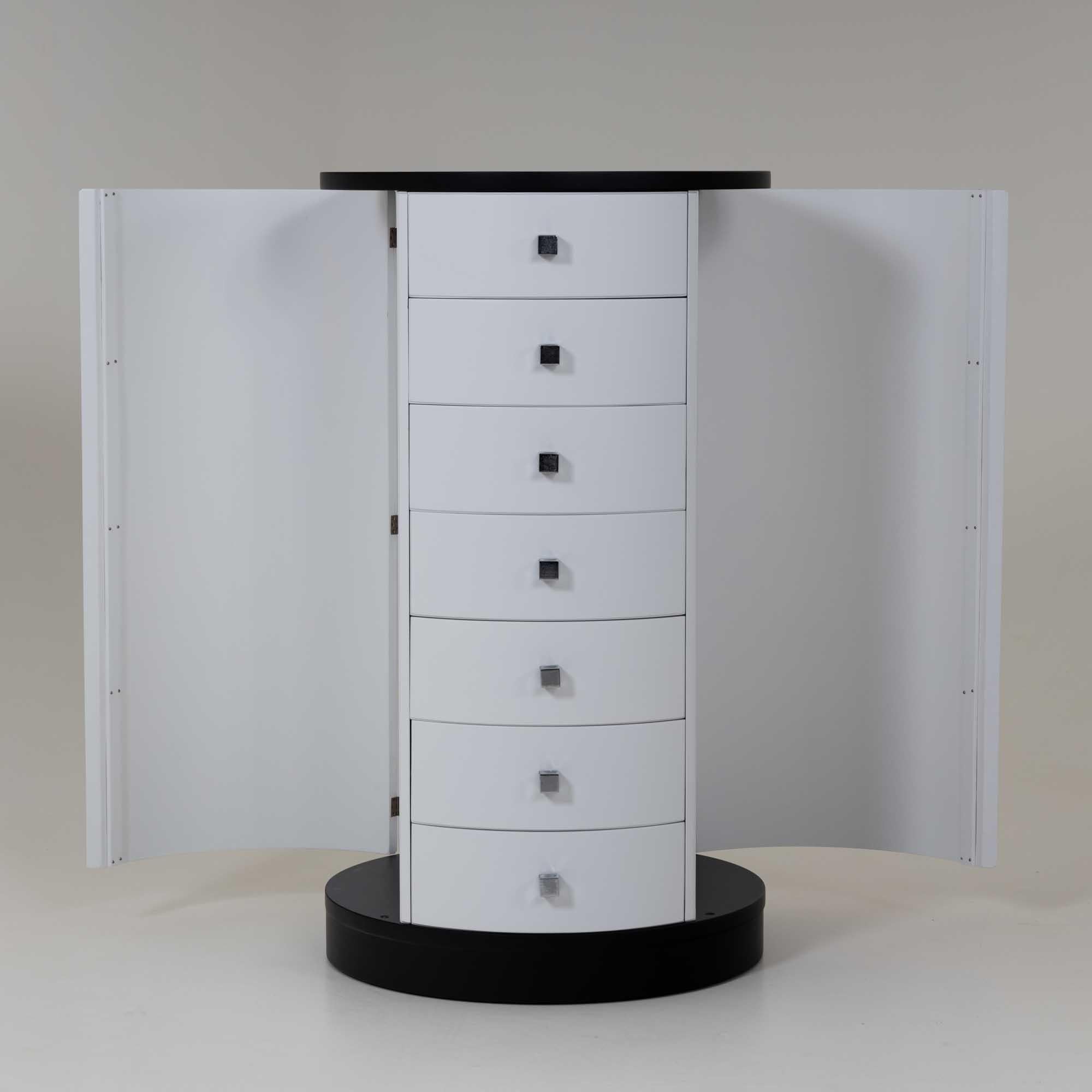White high chest of drawers with chrome-plated handles and black lacquered top and base. The chest of drawers was designed by Ico Parisi for Fratelli Longhi. The cylindrical shape and the use of seven drawers represent an interesting play on the