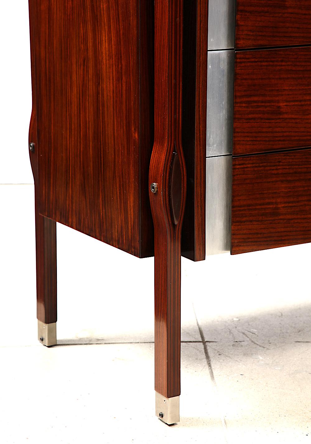 Rosewood, aluminum, brass. Chest of drawers from the Taormina line for MIM. 4 drawers with hidden locking side panel. Fantastic design with curved wood legs and elliptical slab-stretchers. Original lock key included.