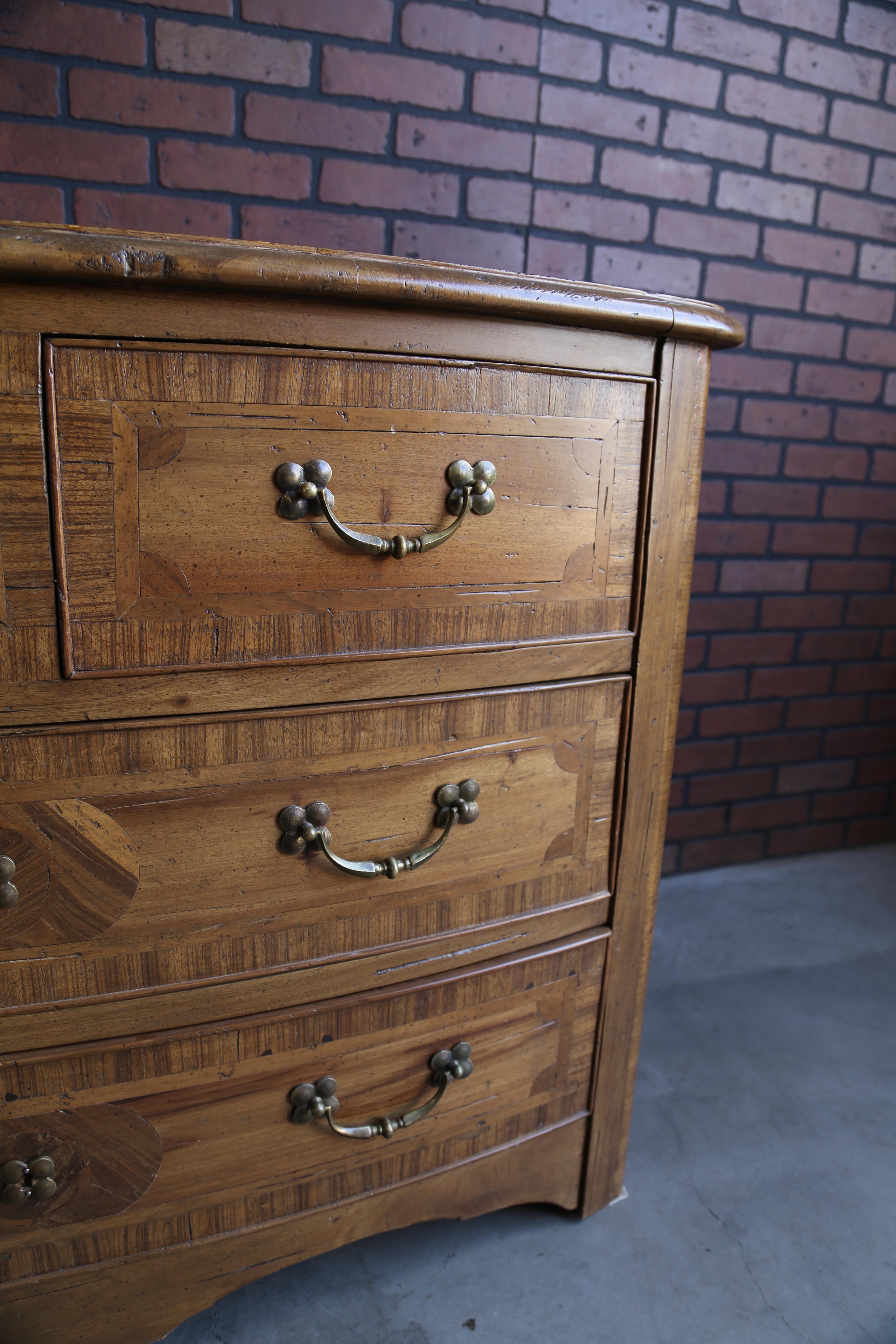 Cassettiera eccezionale per stile e qualità. L'impiallacciatura a più motivi è un'opera d'arte. È caratterizzato da una ferramenta a gancio in stile francese, da un design frontale curvo e da un grembiule smerlato a doppio arco. Questo mobile si