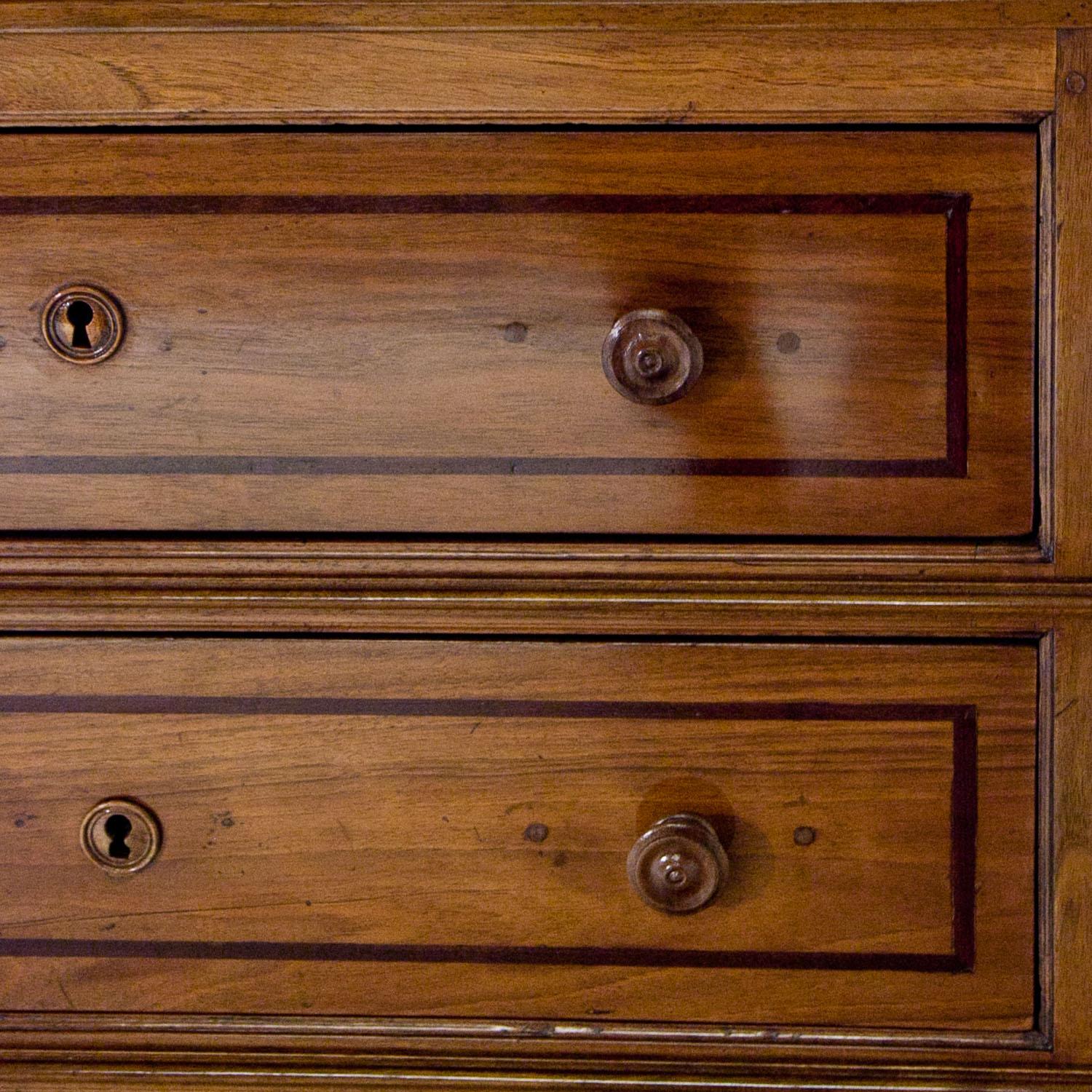 Small three-drawer commode on scroll feet, with a stepped skirt and profiled trusses. The top and the front with frame fillings.