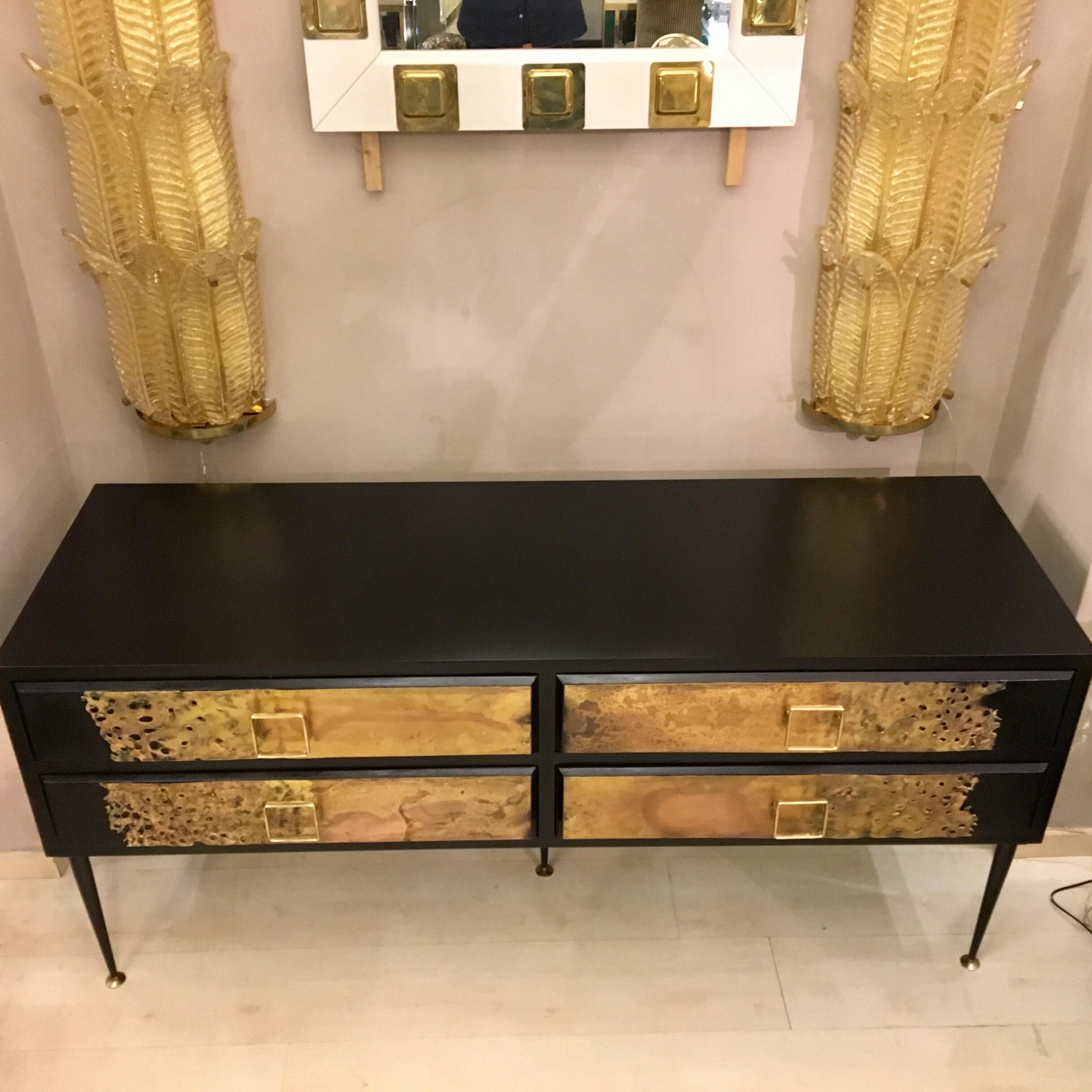 Chest of drawers in black lacquered wood, four drawers frontal application of sculpture effect brass plates, brass square handles.
