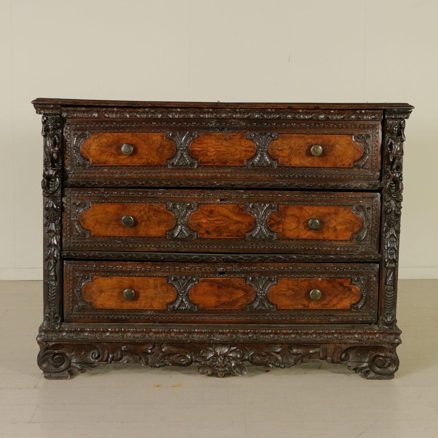 An important chest of drawers with two drawers plus a drop-leaf one. Half drop-leaf opening top that hides a showcase with four drawers and an opened central compartment. Finely carved and perforated uprights with plump children and an underlying