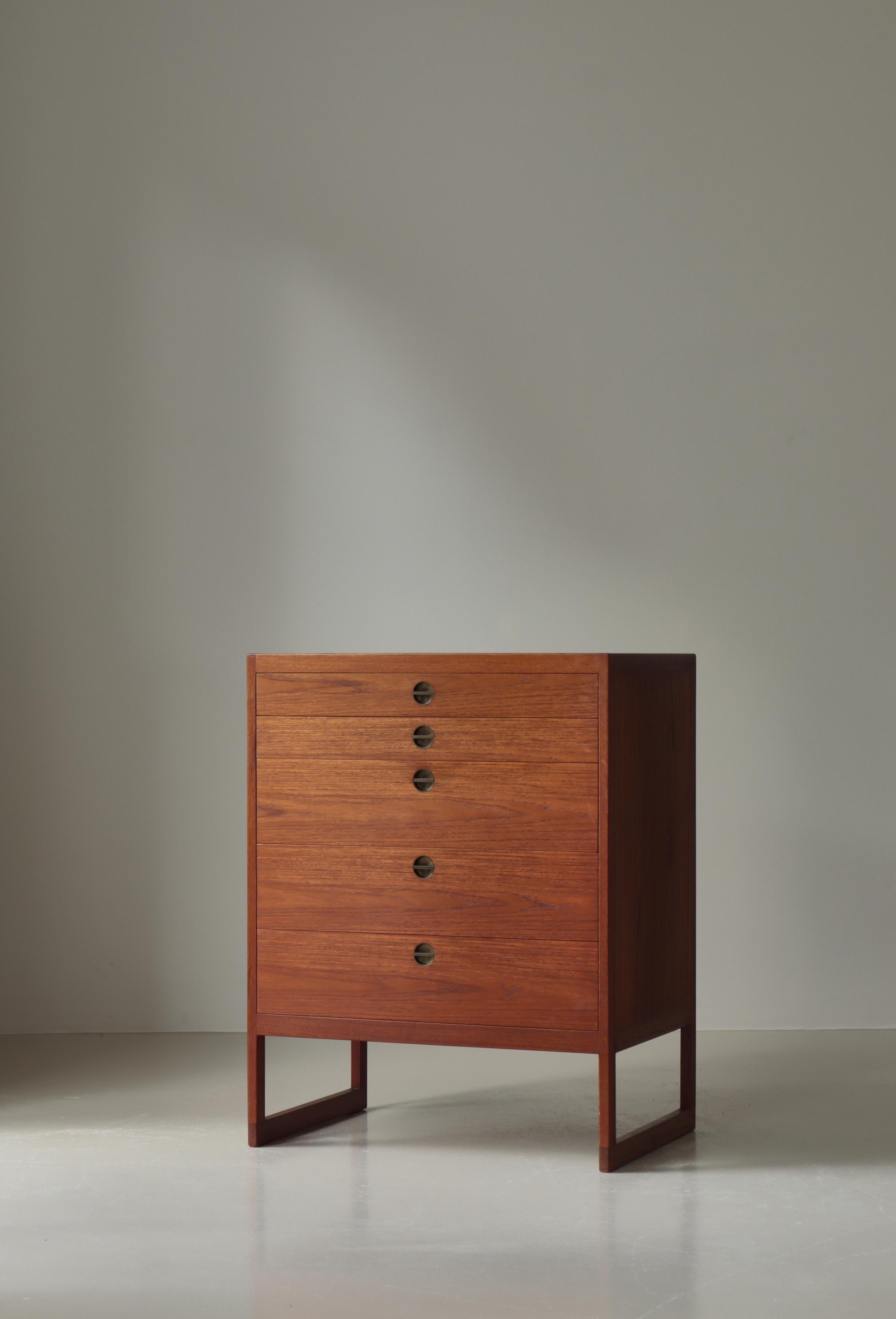 Esta rara cómoda modelo BM57 fue diseñada en 1957 por Børge Mogensen y producida por el ebanista danés P. Lauritsen & Søn. Fabricada en madera de teca maciza, la pieza presenta un acabado oscuro que resalta el veteado natural de la madera. Su forma