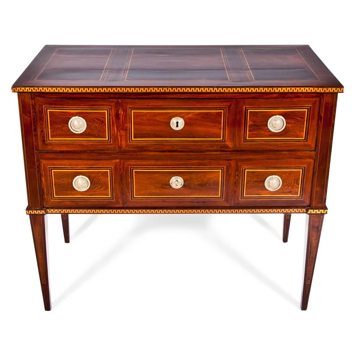 Two-drawered chest of drawers on tall tapered legs. The chest shows a beautiful walnut veneer with maple inlays on the top, front and meander strips on the edges.