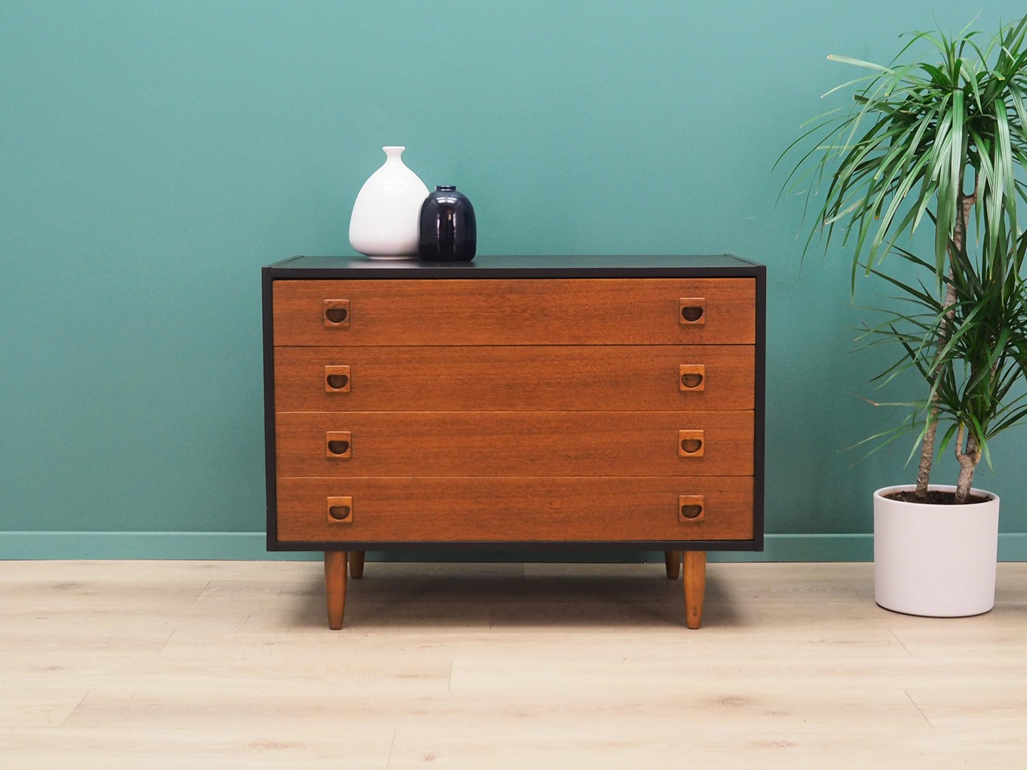 Chest of drawers was made in the 1970s, Danish production.

The construction is made of wood painted black. The legs and handles are made of solid teak wood. The surface after refreshing. The cabinet is a classic chest of drawers, ideal for any