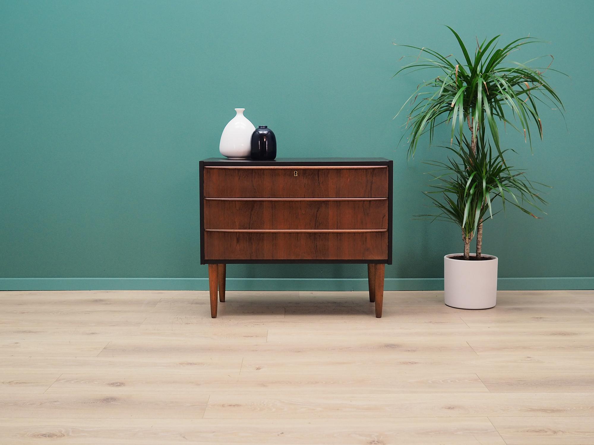 Superb chest of drawers from the 1960s-1970s, Danish design, Minimalist form. Surface of the furniture covered with teak veneer, legs made of solid teak wood. Top is colored in black. Furniture has three spacious drawers, no key. Preserved in good