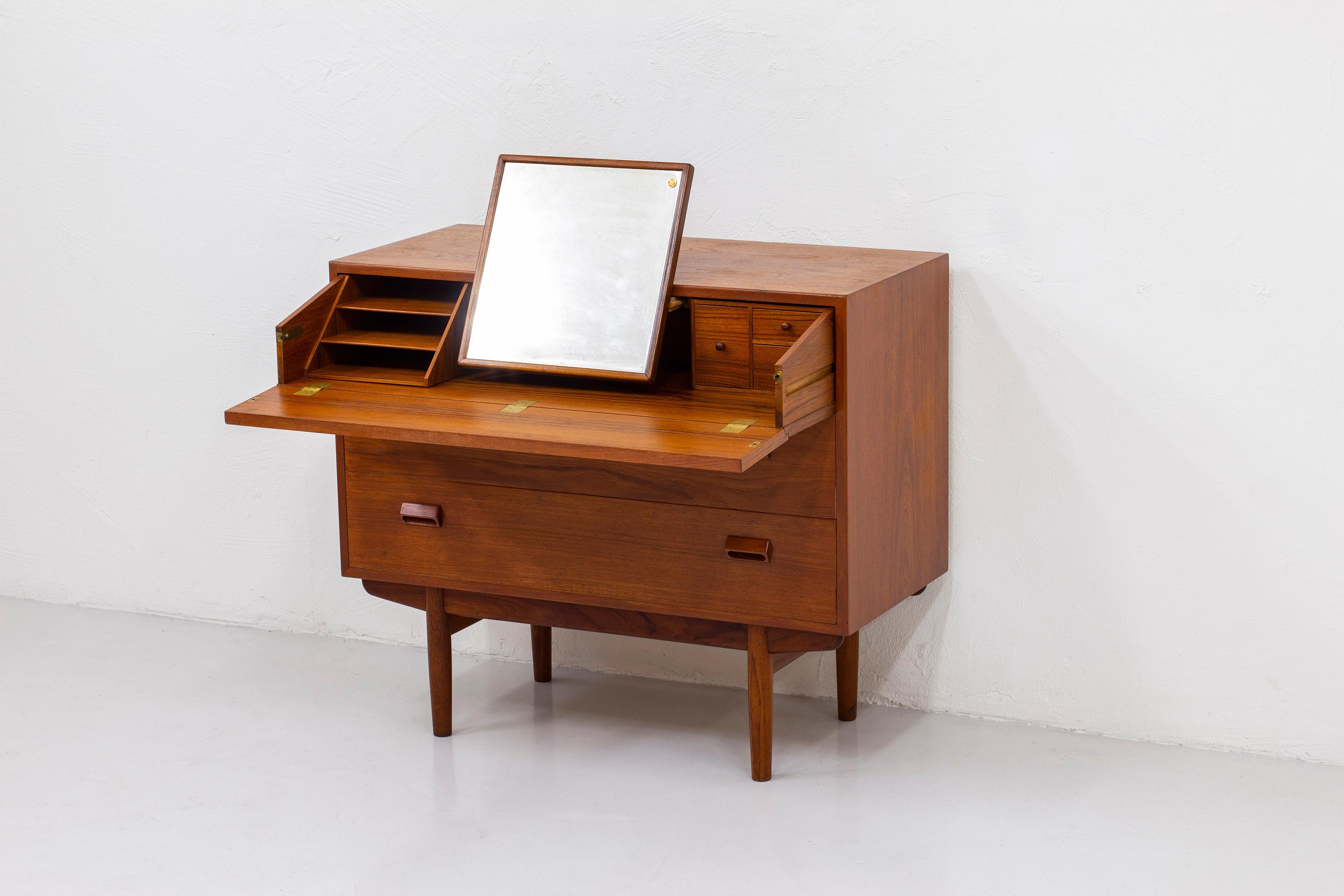 Chest of drawers with built in vanity mirror and flip down table surface designed by Børge Mogensen. Produced in Denmark by Søborg during the 1950s. Made from teak with brass details. Inside of the drawers with maple. good vintage condition with age