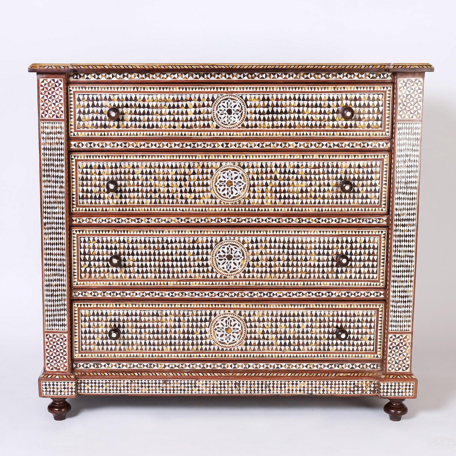 Moroccan four drawer chest fit for a king, crafted in mahogany with a floral inlaid cartouche on the top and sides inside a field of mother of pearl, indigenous hardwoods and bone marquetry with multiple inlaid borders. The drawer fronts have center
