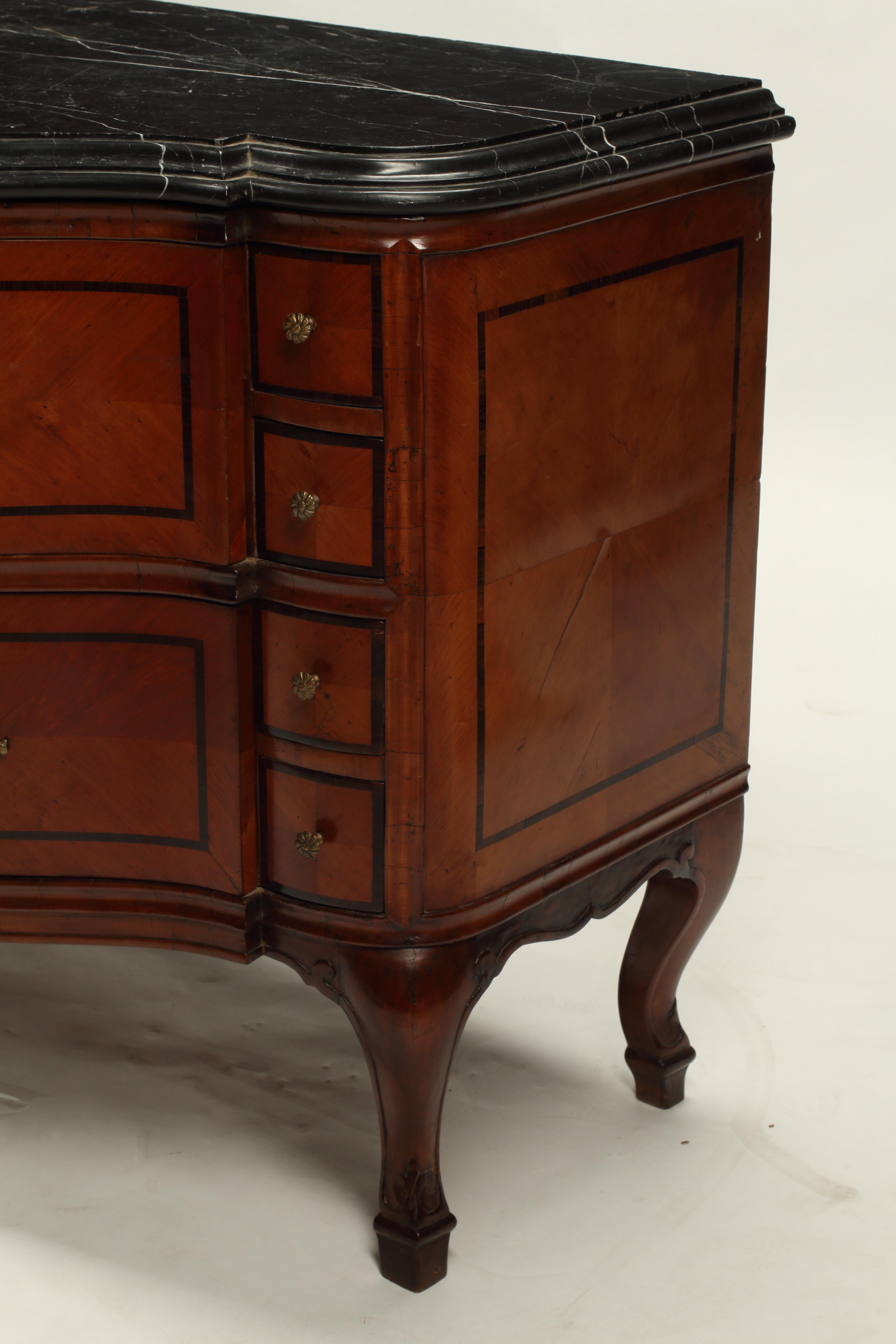 Questa cassettiera svizzera del XVIII secolo è un ottimo esempio di artigianato di alto livello dell'epoca. La cassapanca presenta una forma a bombe e uno splendido piano in marmo nero. I frontali dei cassetti sono intarsiati con impiallacciatura di