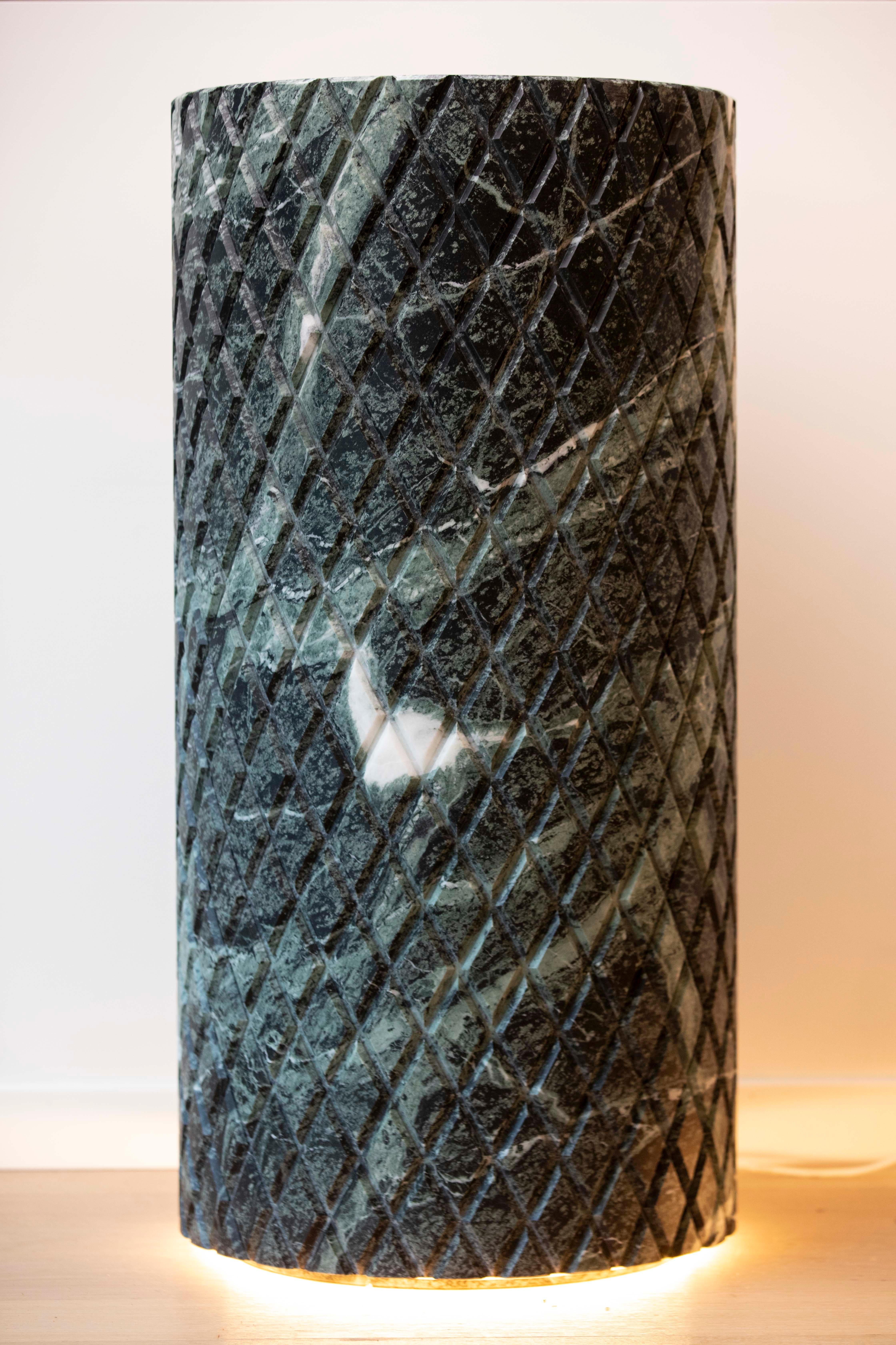 This pedestal, crafted from Verde Alpi  marble, exudes a sense of timeless elegance that recalls elements of Art Deco design. Its striking geometric pattern of diamond-shaped carvings emphasizes symmetry and precision, characteristic of the 1920s