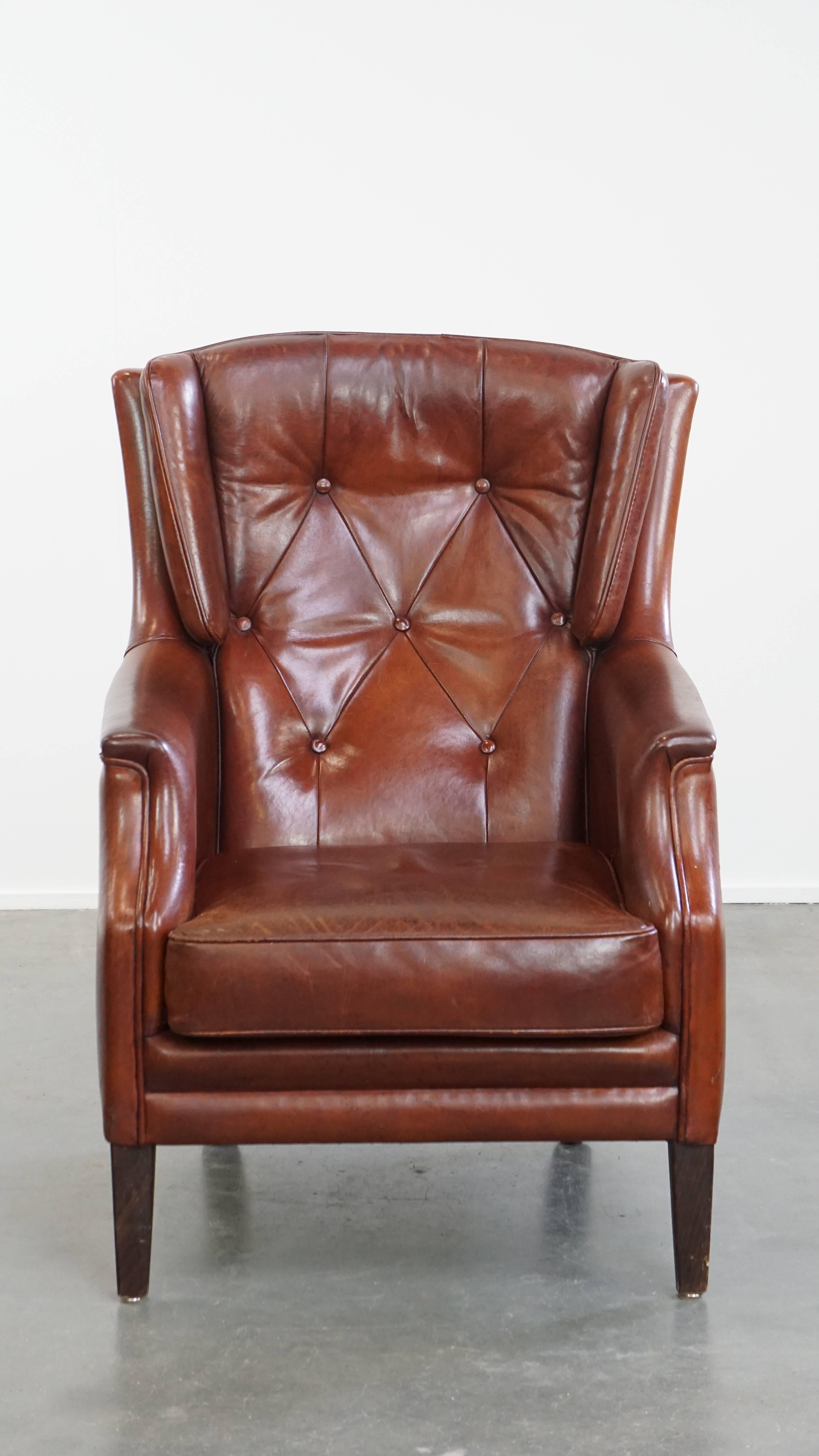 Te ofrecemos este elegante sillón Chesterfield de piel de oveja con un aspecto cálido y con carácter. 

Este cómodo sillón presenta piel de oveja de alta calidad y un refinado acabado con ribetes de colores a juego. La silla viene con un cojín de
