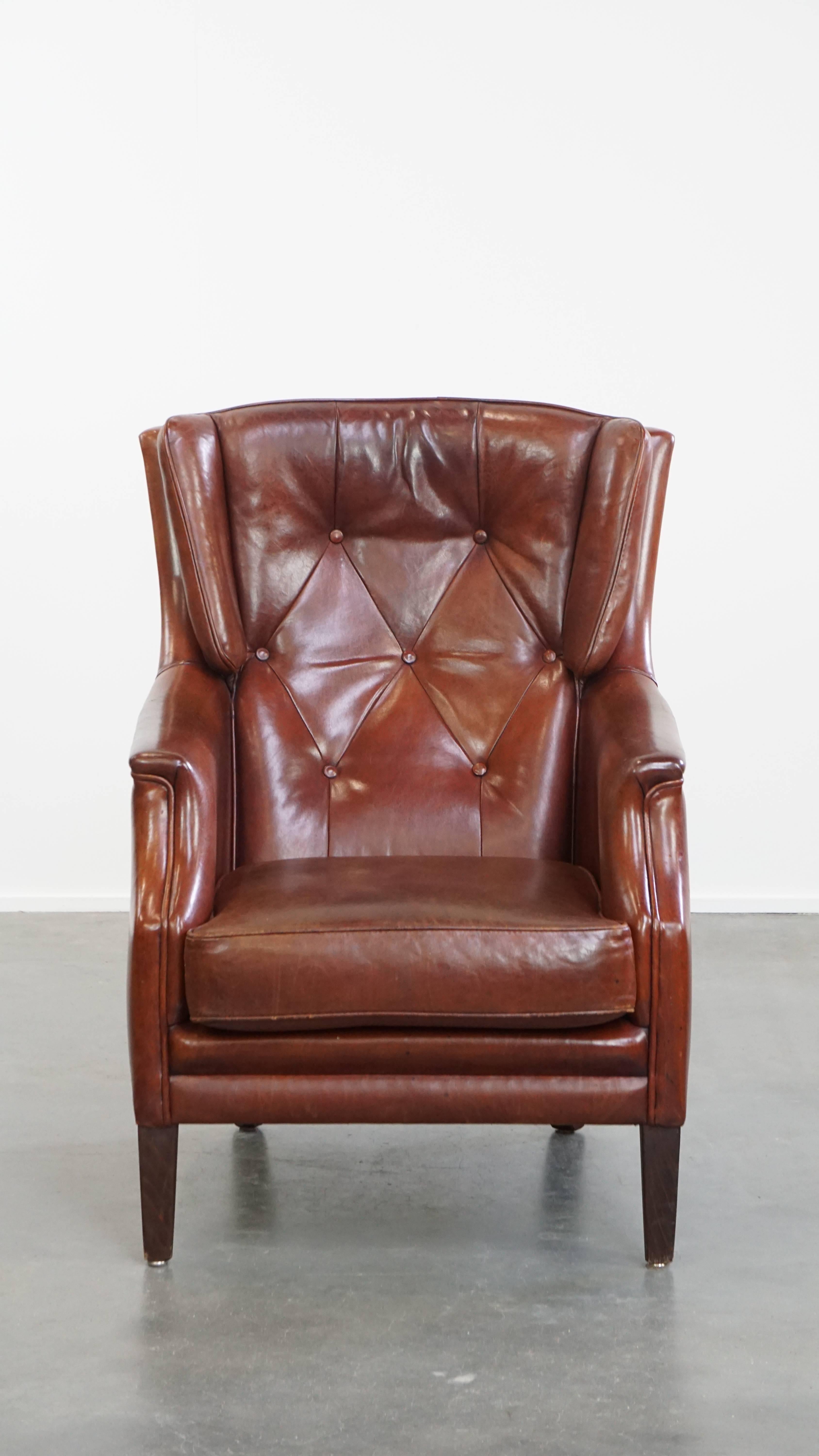 Angeboten wird dieser bequeme und charaktervolle Chesterfield-Sessel mit Ottomane, der aus Schafsleder gefertigt ist. Dieses elegante Set aus Sessel und Ottomane ist aus Schafsleder gefertigt und mit raffinierten Paspeln in passenden Farbtönen