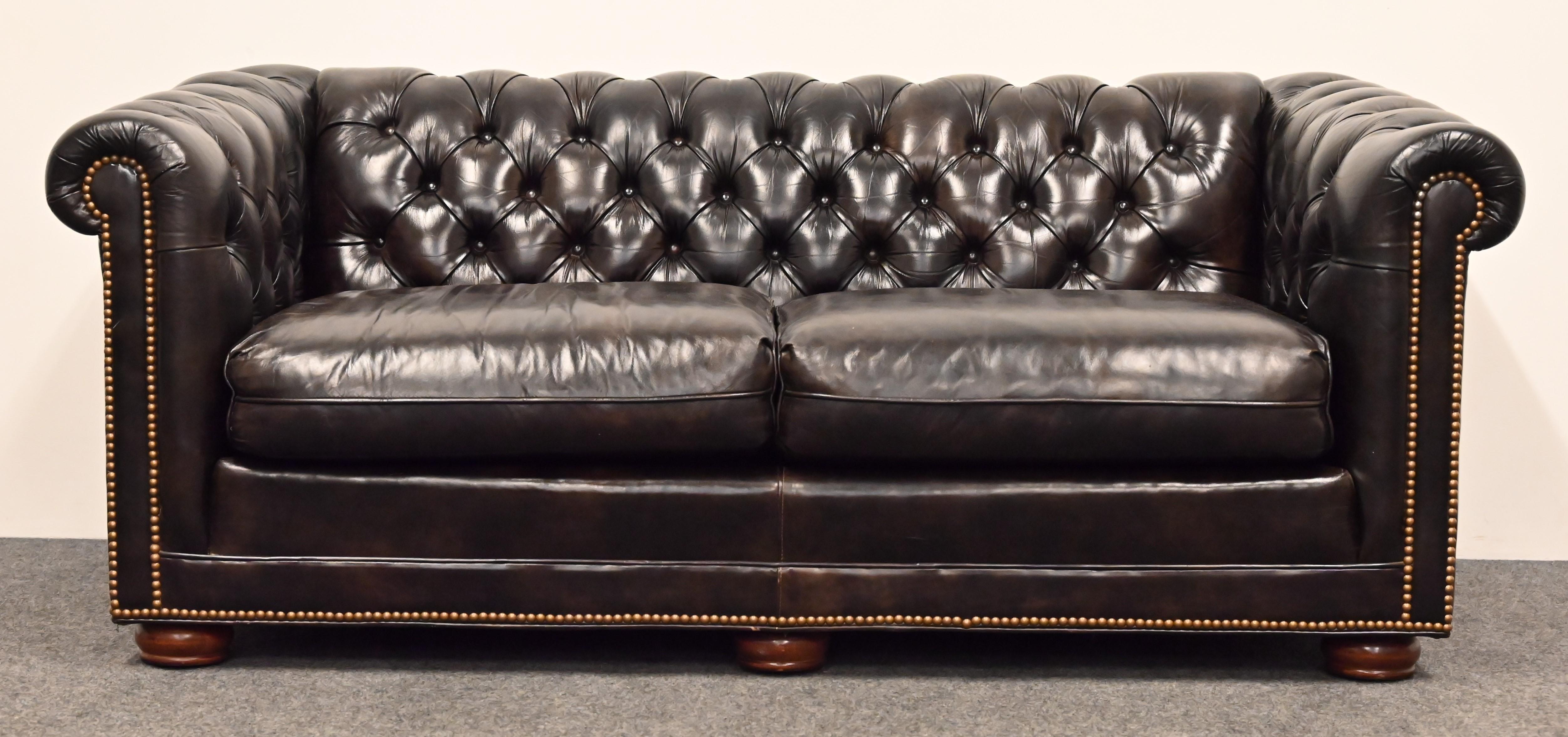 A handsome and luxurious espresso brown leather loveseat or sofa. This gorgeous settee was made by Leathercraft. The brass nailheads add a very refined touch with its solid maple wood bun feet and rolled arms and tufted seat. Would look good in any