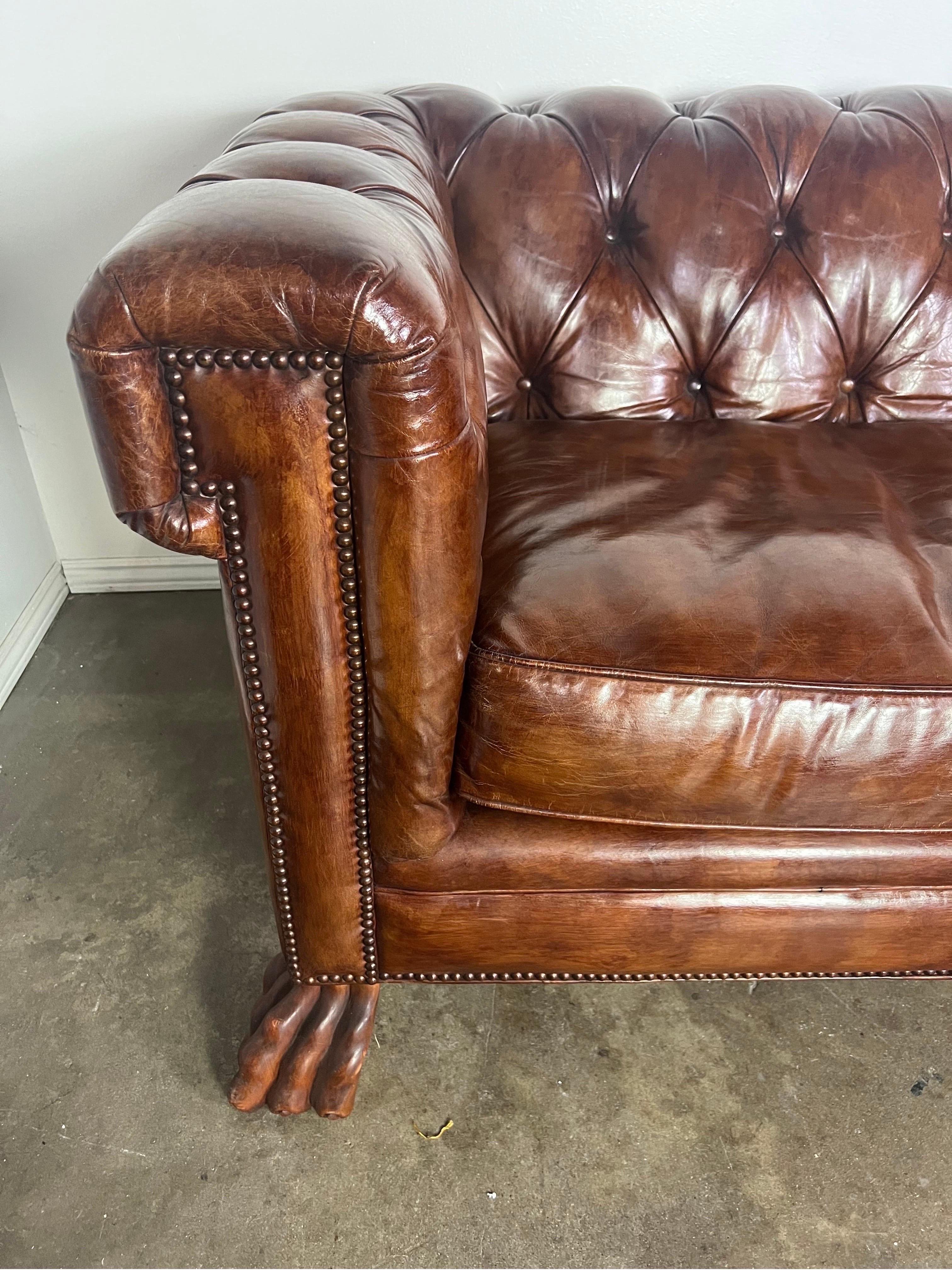 Rich leather tufted Chesterfield style sofa with loose cushions and nailhead trim detail.  The arms have a unique shape and add a modern twist to an old classic style sofa.