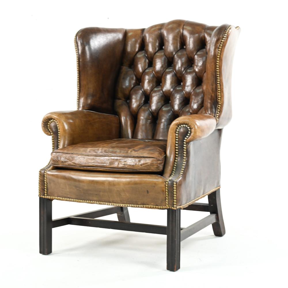 A handsome Chesterfield wingback lounge chair in tufted leather with brass nailhead trim.