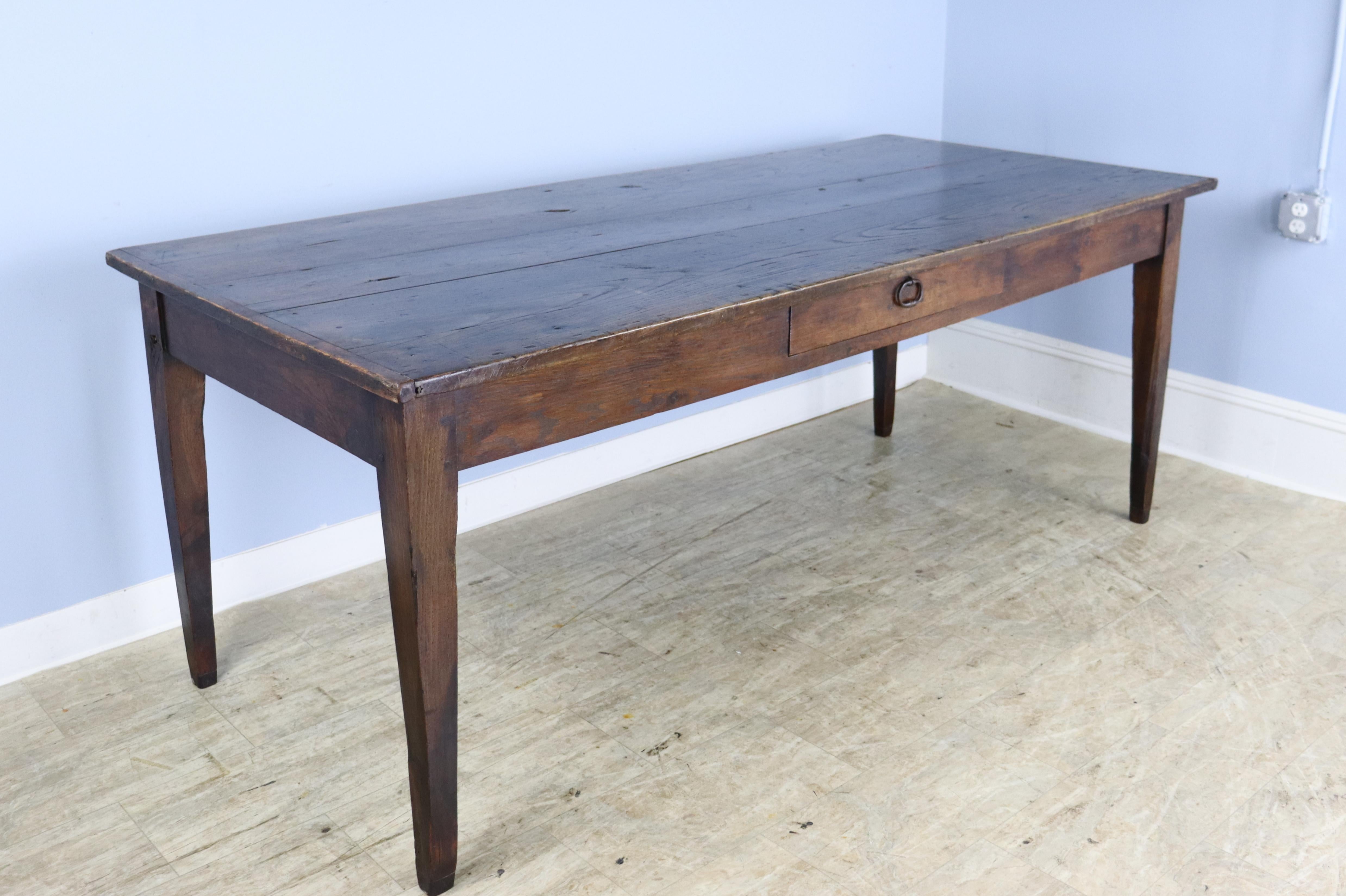 An elegant chestnut farm table with two roomy drawers amd small breadboard ends. Well grained tapered legs, pegged at the apron. 24.25 inch apron height is good for knees and there are 70.5 inches between the legs on the long side. The top is some