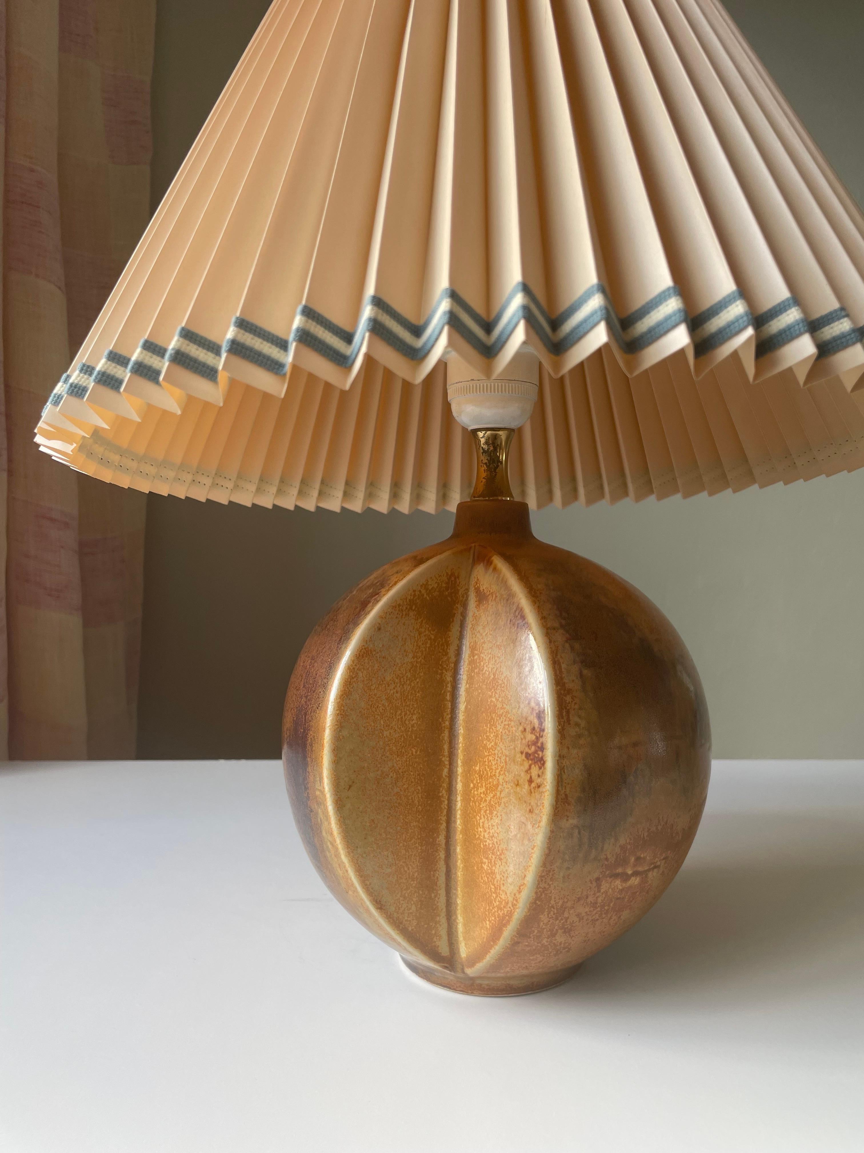 Golden chestnut brown, amber and black colored globe shaped ceramic table lamp with two sculptural 