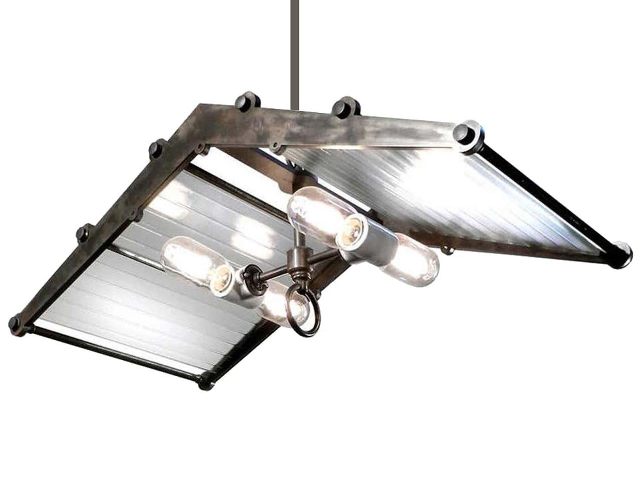 This oversized pendant features a substantial 12 x 24 inch frame designed for the early ribbon glass panels. The glass casts a beautiful 3D glow. The blackened brass and steel frame tents over four floating horizontal tubular bulbs using porcelain