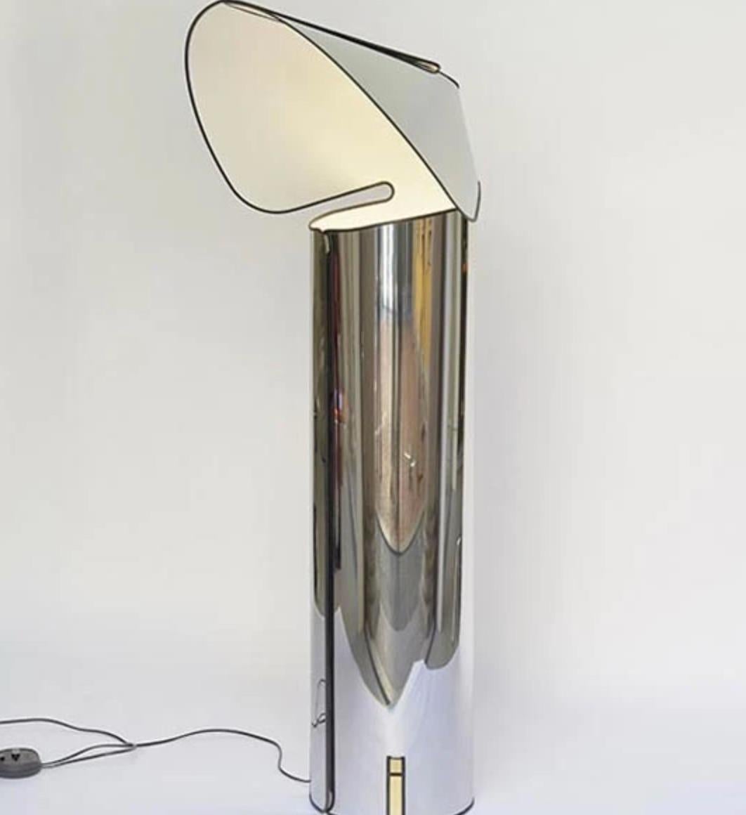 Le lampadaire Chiara, dessiné par Mario Bellini pour Flos, conçu à l'origine en 1969, est un modèle emblématique formé d'une simple feuille d'acier inoxydable poli qui a été découpée et roulée en cylindre. Cette structure en forme d'origami