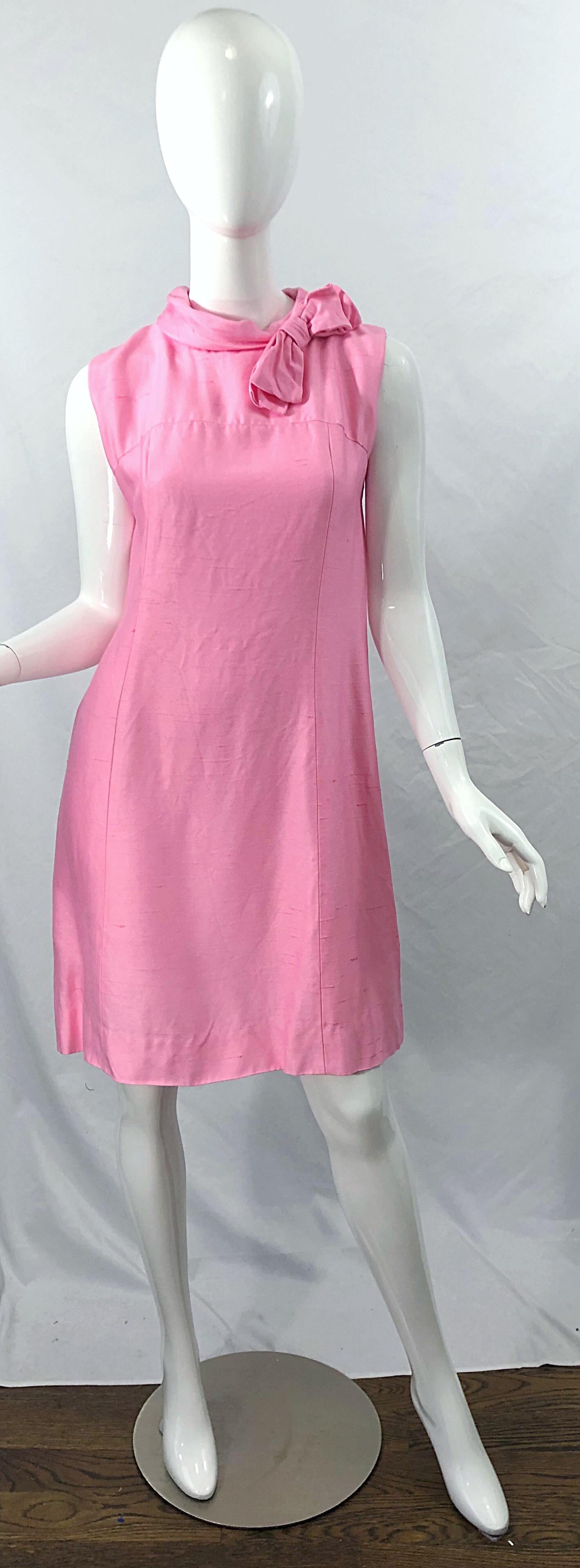Chic 1960s bubblegum pink Jackie O style silk dress! Flattering sheath shape with a bow at top left center neck. Full metal zipper up the back with hook-and-eye closure. Perfect for any day or evening event. Pair with flats, sandals or wedges for