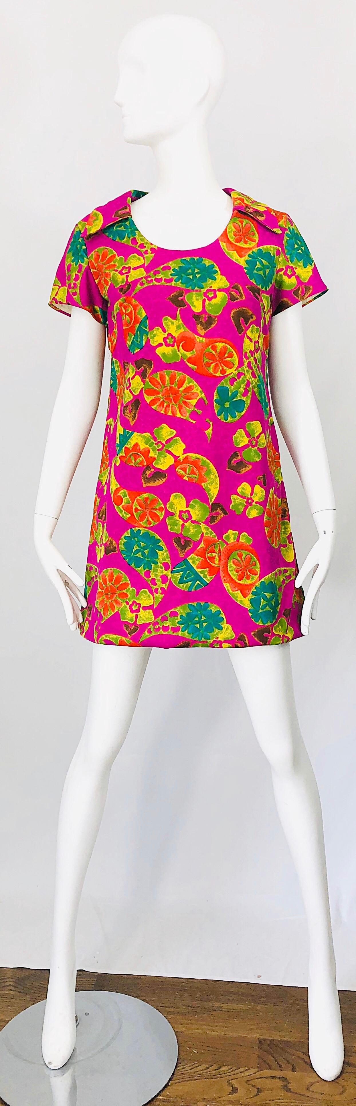 Chic 1960s Hawaiian Tiki print fuchsia pink cotton tunic / mini dress! Features vibrant colors of pink, purple, chartreuse, kelly green, and orange throughout. Hidden metal zipper up the back with hook-and-eye closure. There is seam allowance to