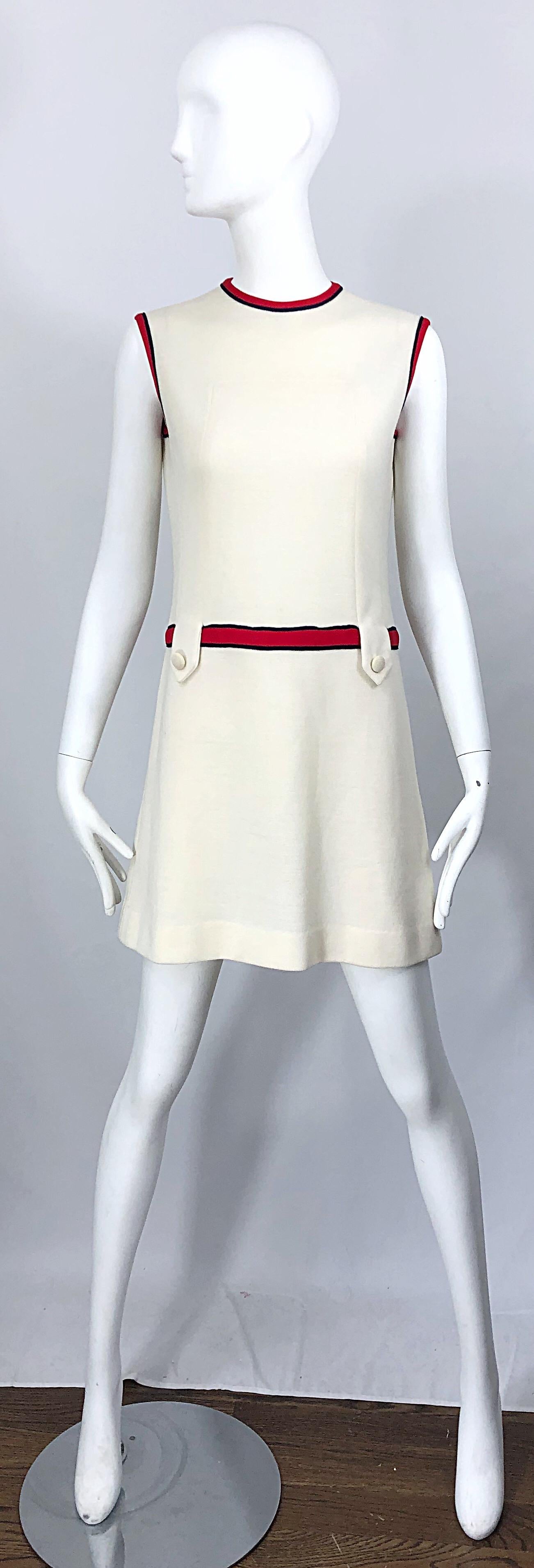 Chic 1960s ivory, navy blue and red knit scooter / shift dress! Features soft ivory knit that has plenty of stretch. Two loops and buttons at each side of the front waist. Hidden metal zipper up the back with hook-and-eye closure. Great with