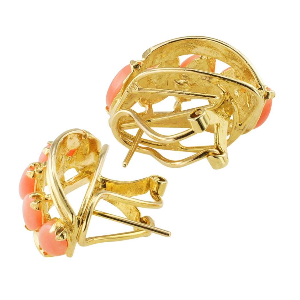 Estate 1980s salmon-pink coral and gold earrings. Matching demi-hoop designs centering upon a course of five marquise-shaped salmon pink corals set on a horizontal plane with open work to fluted gold borders, mounted in 14-karat yellow gold, the