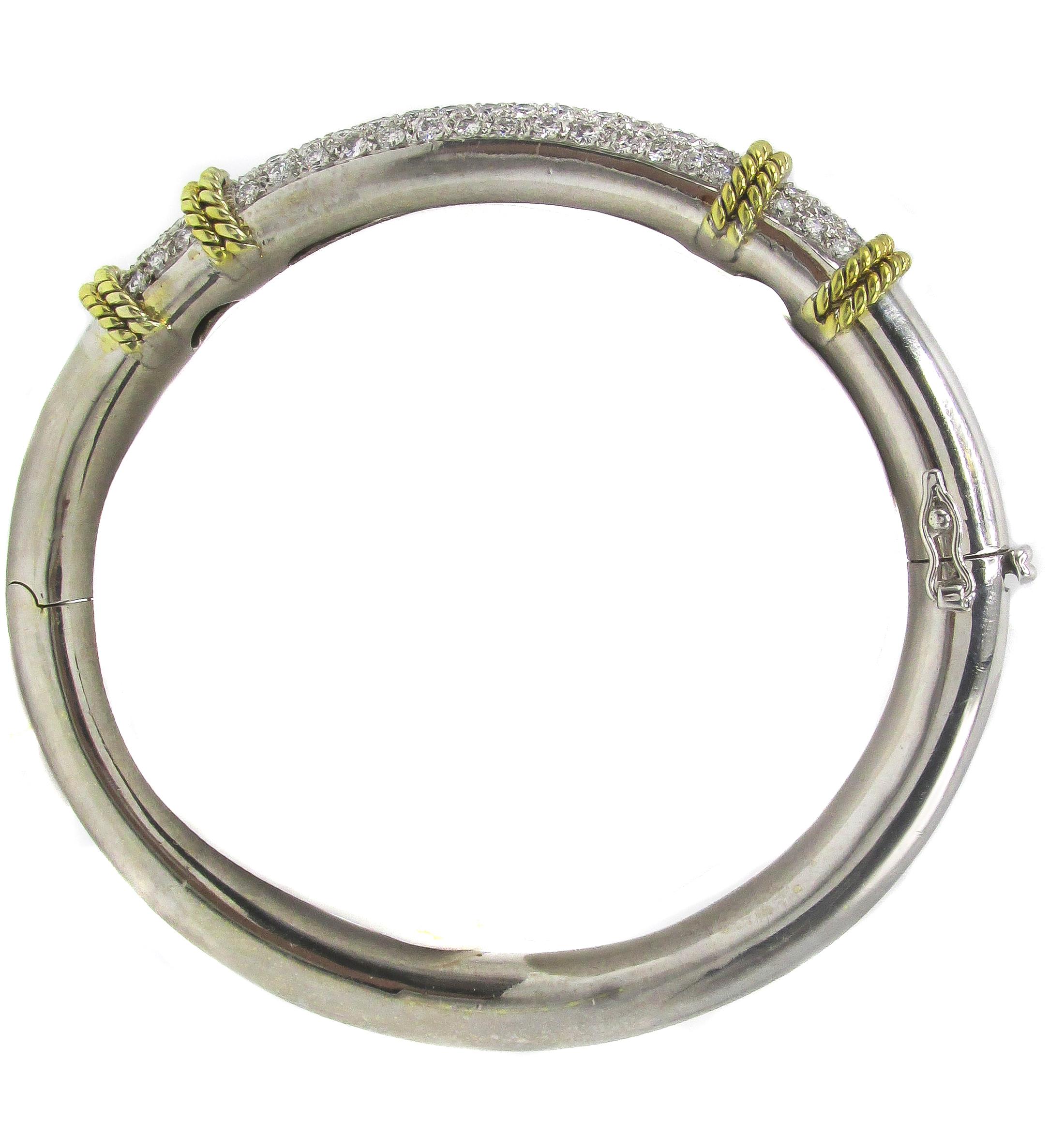 Chic 18 karat white and yellow gold bangle bracelet set with 80 bright white round brilliant cut diamonds weighing approximately 2.25 carats. The meticulously pave set diamonds show off an amazing sparkle and are elegantly separated into 3 sections