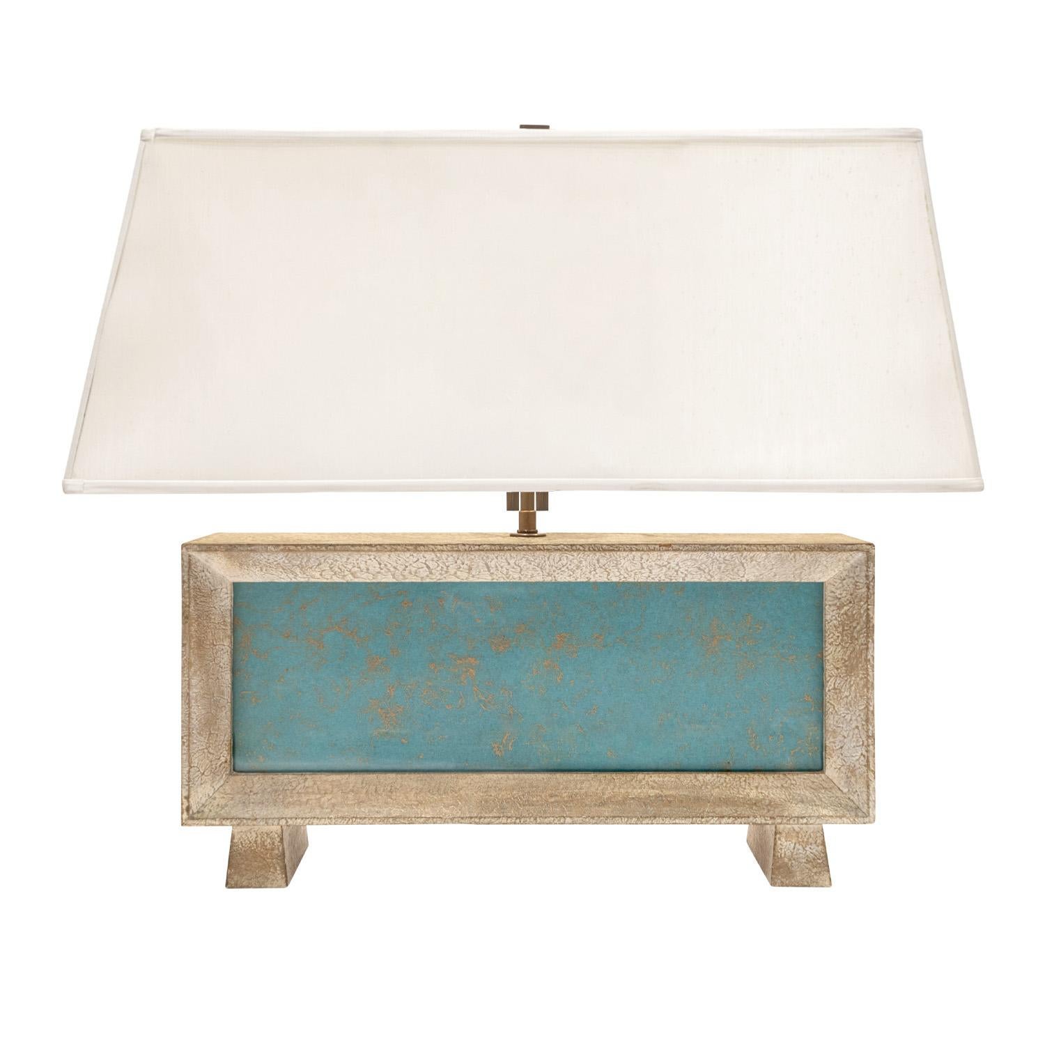 Boxy table lamp with textured gold and white resin finish and illuminating blue and gold reverse-painted glass front panel, American 1940's.  This lamp is stunning and enchanting when the backlit panel is illuminated.  Rewired by Lobel Modern. 