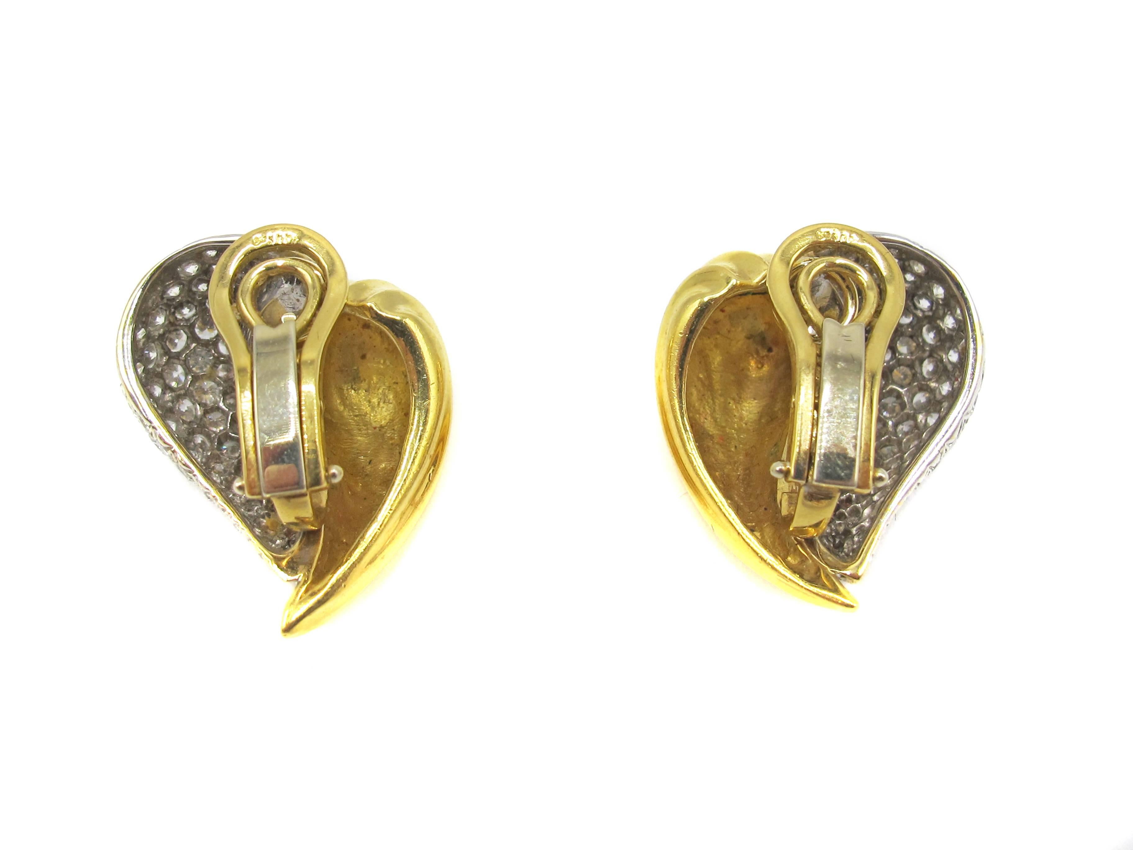 Chic 18 karat white and yellow gold ear clips designed in the shape of a pair of intertwining leaves. The amazing craftsmanship and design of these hand crafted ear clips bring this three dimensional creation to life on the ear. One section of