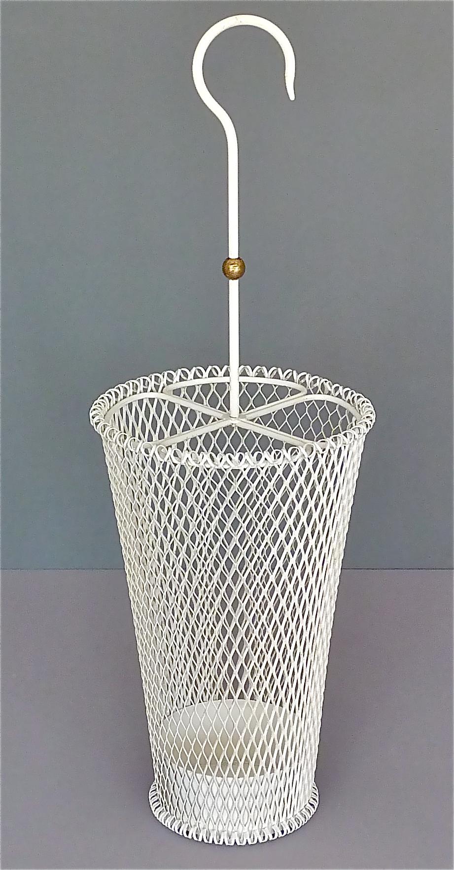 Elegant midcentury umbrella stand in the style of Mathieu Matégot, Jacques Biny or Pierre Guariche, France, circa 1955. It has a white enameled stretched metal body and a simple and chic white enameled iron handle with a nice patinated brass detail.