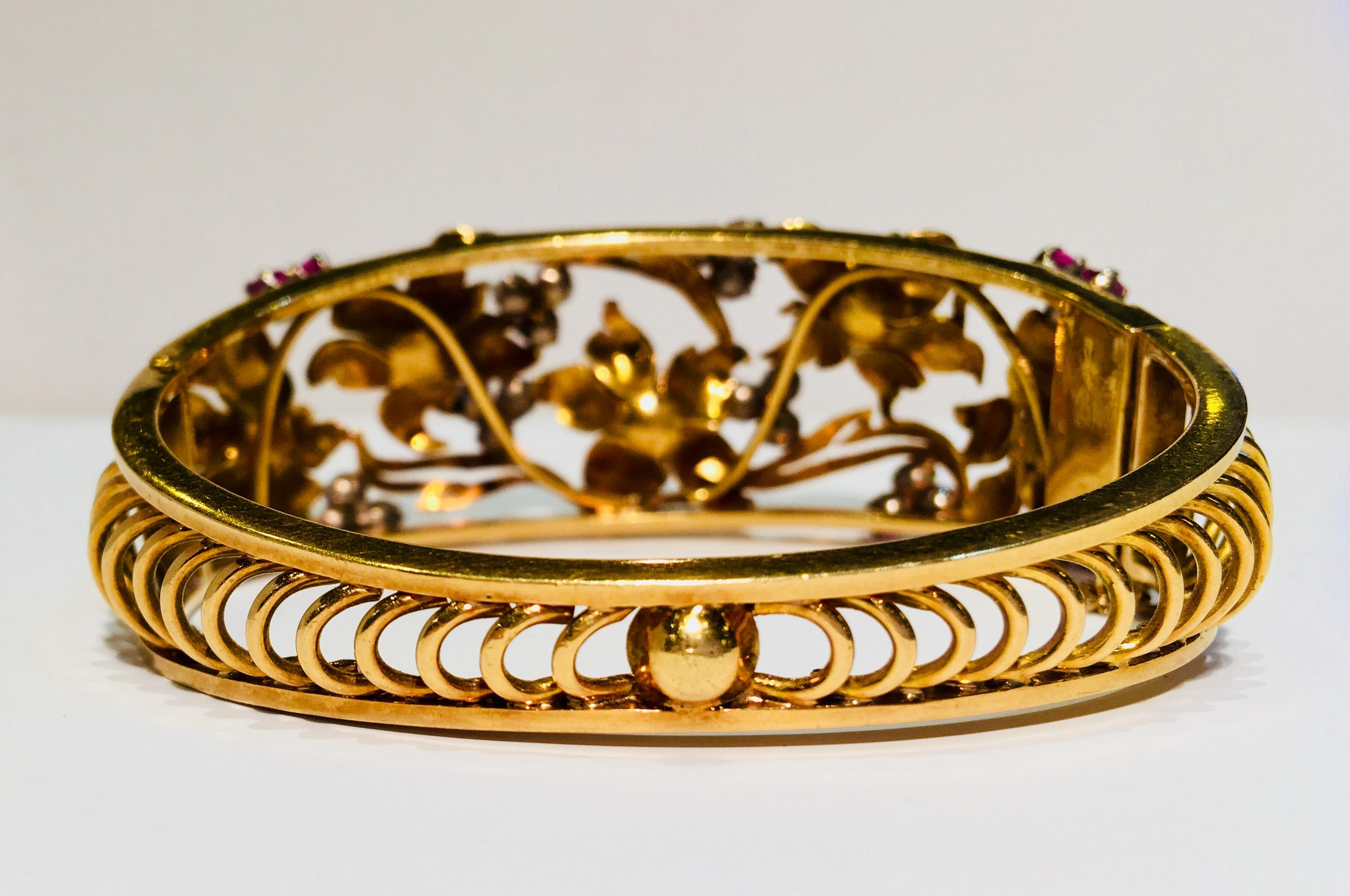 Gorgeous, handmade, 18 karat yellow gold floral estate bracelet from the early 1900s has the graceful flowing lines of stylized, intertwined flowers and leaves popularized by the Art Nouveau movement.

Tapered, hinged bangle bracelet features 5