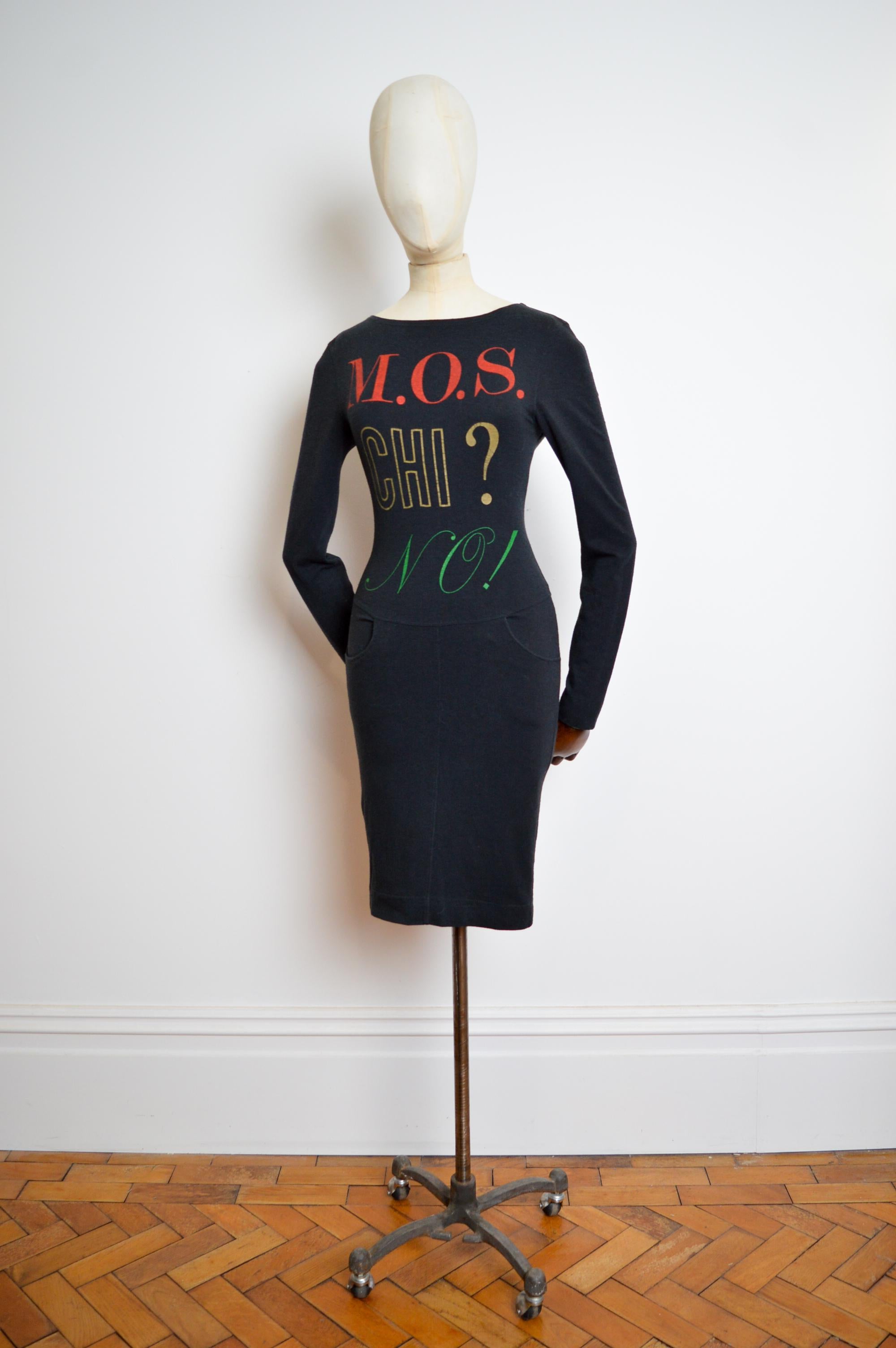 Mini vestido de manga larga con body con de los años 90 Little Black MOSCHINO 
FABRICADO EN ITALIA 
Vestido de cóctel de punto negro elástico de Franco Moschino de principios de los 90 con Mos - chi ? - ¡No! Lema en la parte delantera y divertidos