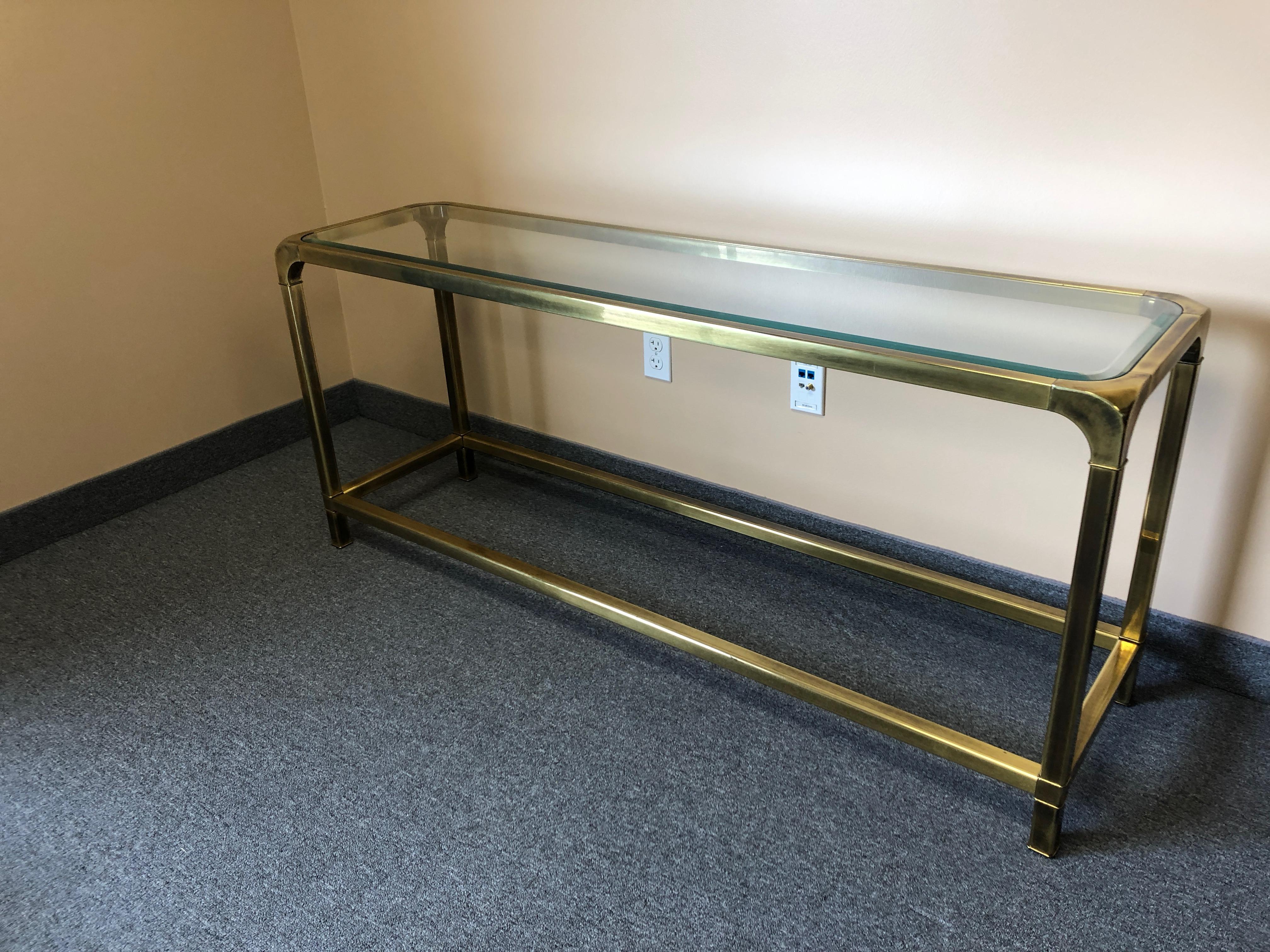 A chic sleek brass and glass console table by Mastercraft that's 26 inches high, perfect for behind a sofa or as a slightly low slung console anywhere.