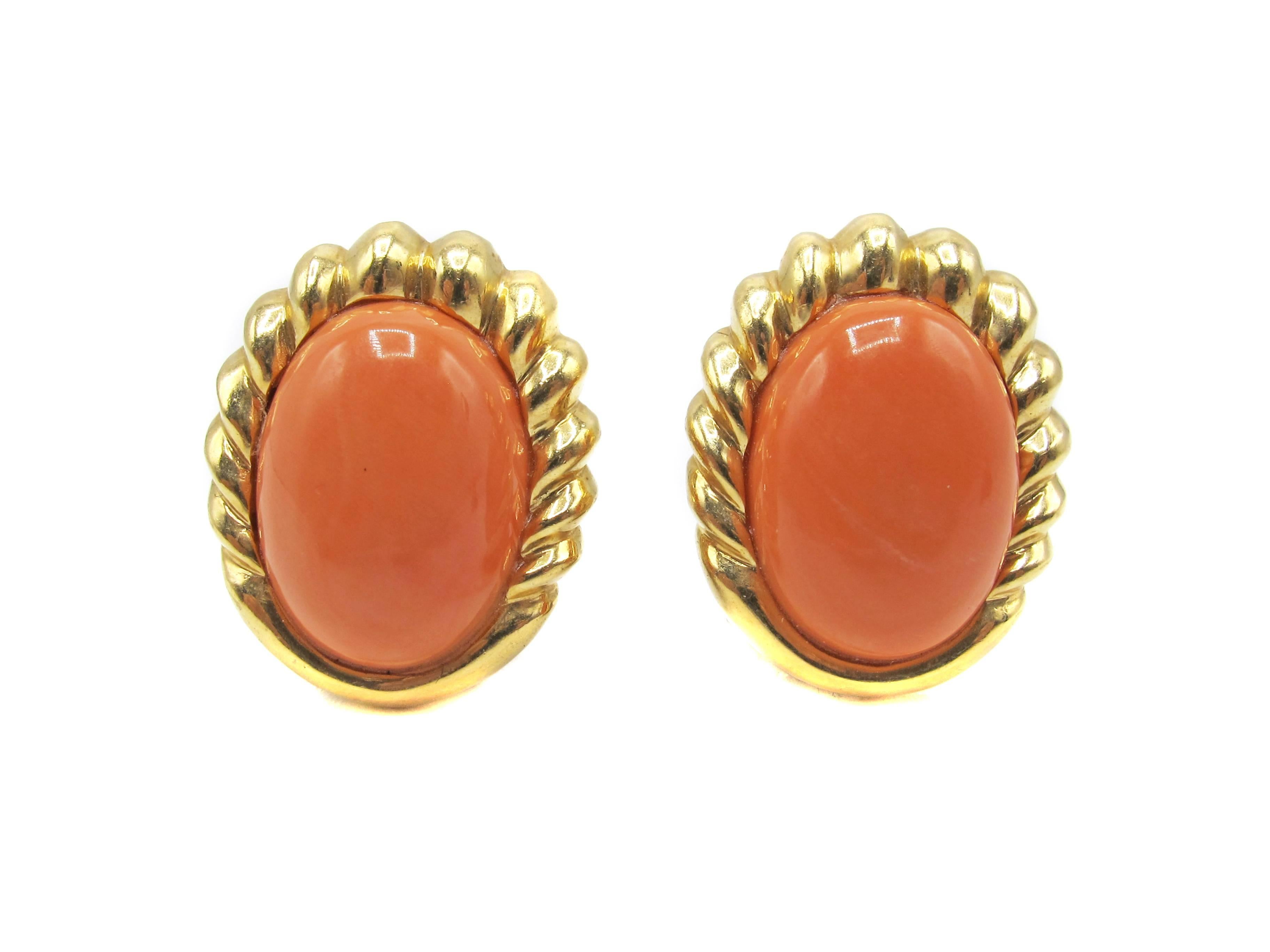 These chic and well hand-crafted ear-clips have a braided bezel which graduates from the top into a band of polished gold. These contain 2 perfectly matched oval cabochon Mediterranean corals which a rich deep pink color. Each piece of coral