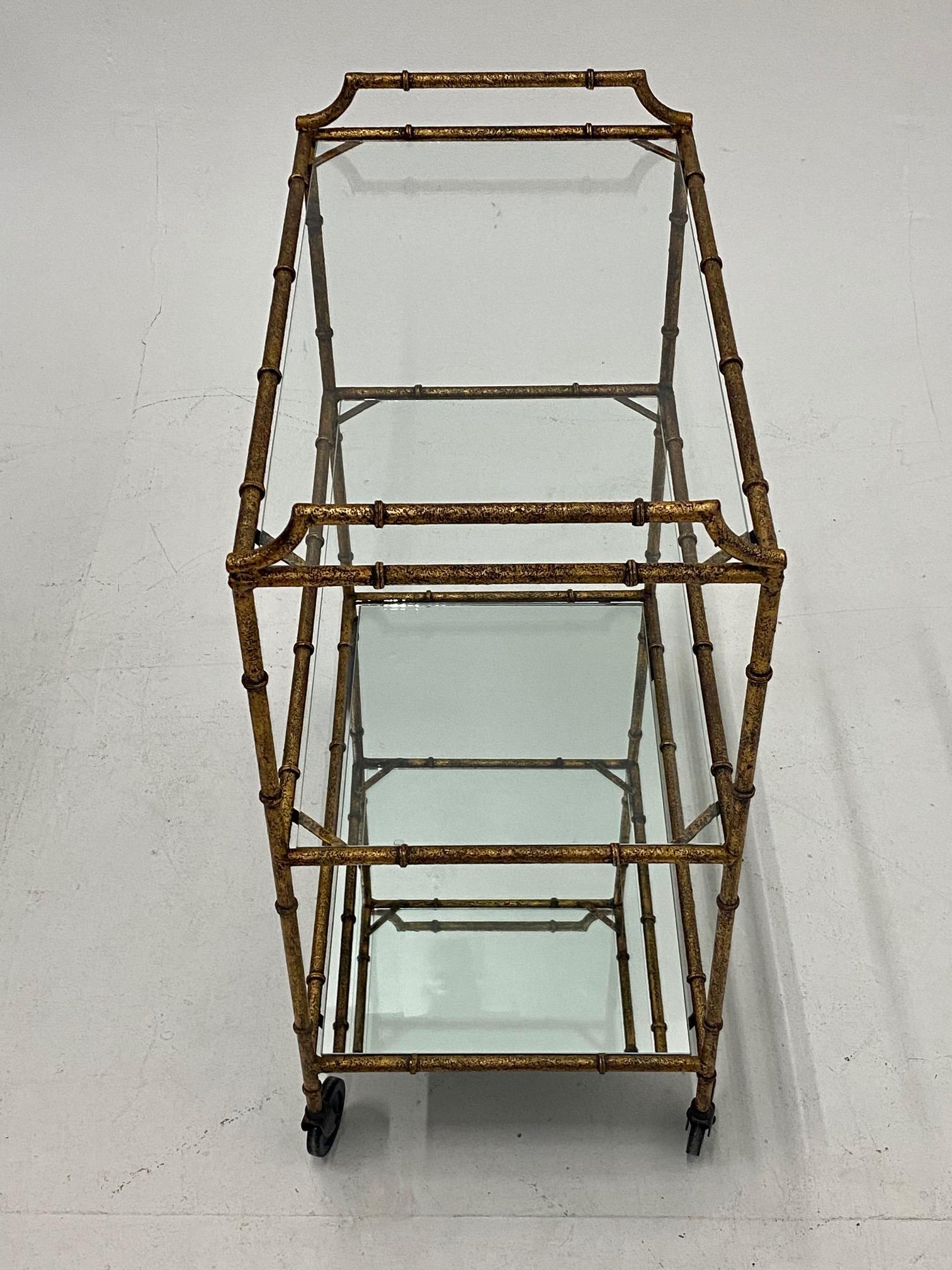 A chic Mid-Century Modern hammered and gilt iron faux bamboo bar cart having 3 glass shelves and smoothly functioning casters. 12