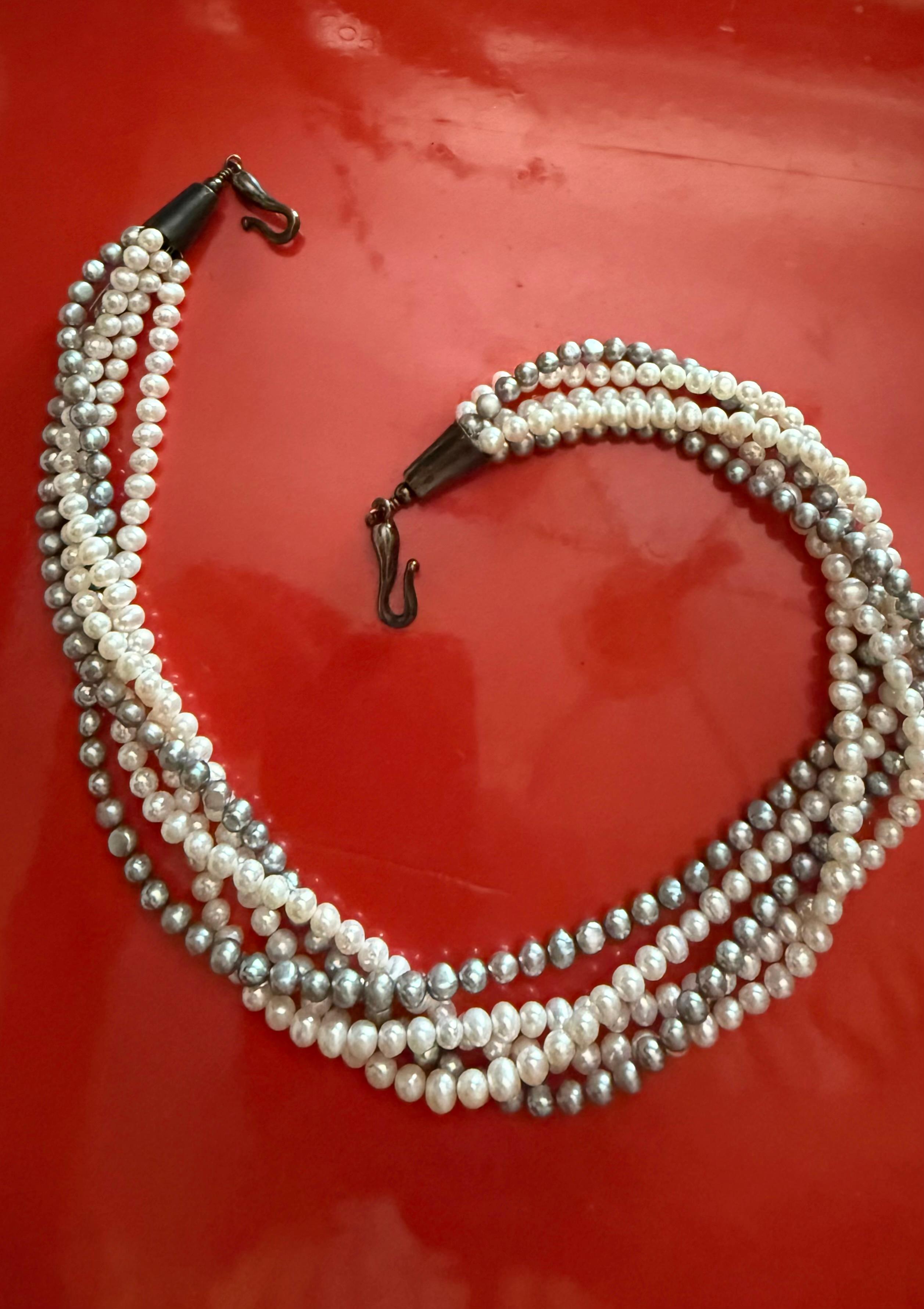 Questa è una collana a torsi elegante e versatile di perle coltivate bianche e grigie. La collana è composta da cinque fili di perle che possono essere indossati sciolti o attorcigliati in una torsione. Ci sono due fili di perle grigie e tre di