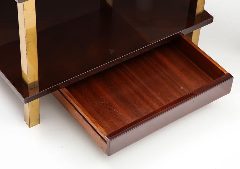Elegant pair that work equally well as end tables or nightstands. The tabletops are lacquered in a deep burgundy red, with finished mahogany secondary wood. Raised on square gilt bronze legs, with drawer on lower shelf. Great build quality. Unsigned