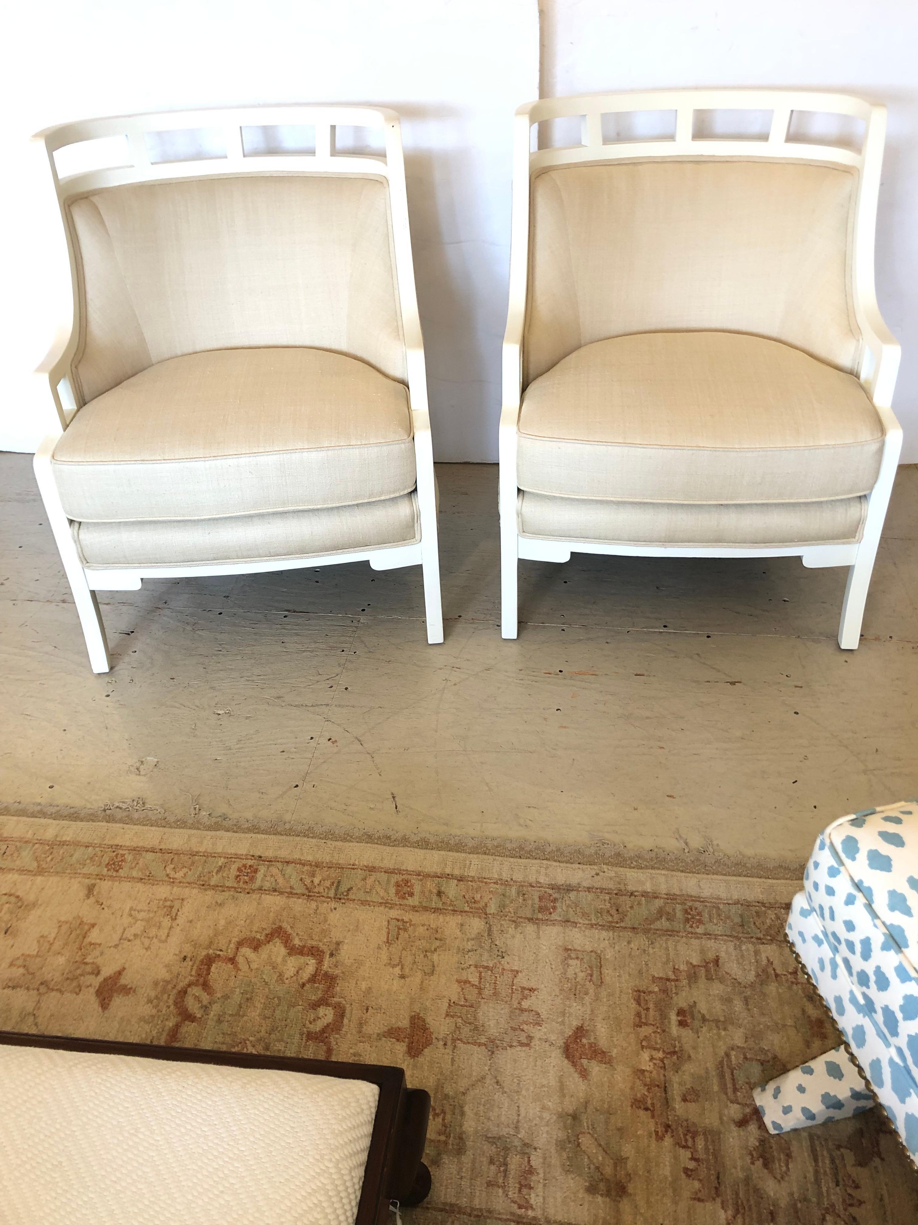 Chic pair of curved barrel back Hollywood Regency club chairs, newly transformed with white paint and natural linen upholstery.