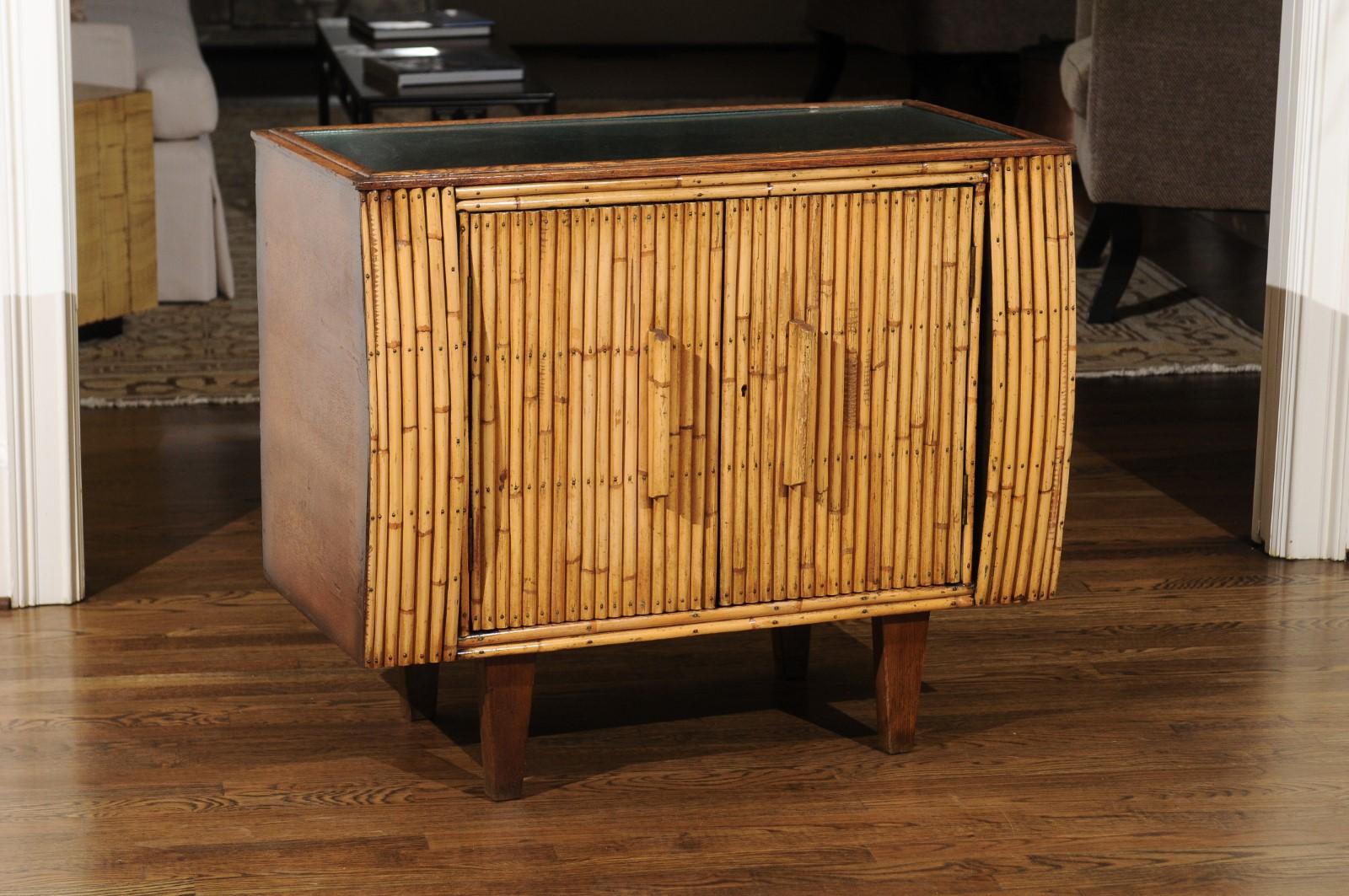 An exquisite Art Deco cabinet, France, circa 1940. Expertly crafted oak construction with a subtle bullnose case detail framing the doors. The cabinet front is veneered in bamboo; simple rattan handles add accent. Interior and accents in black